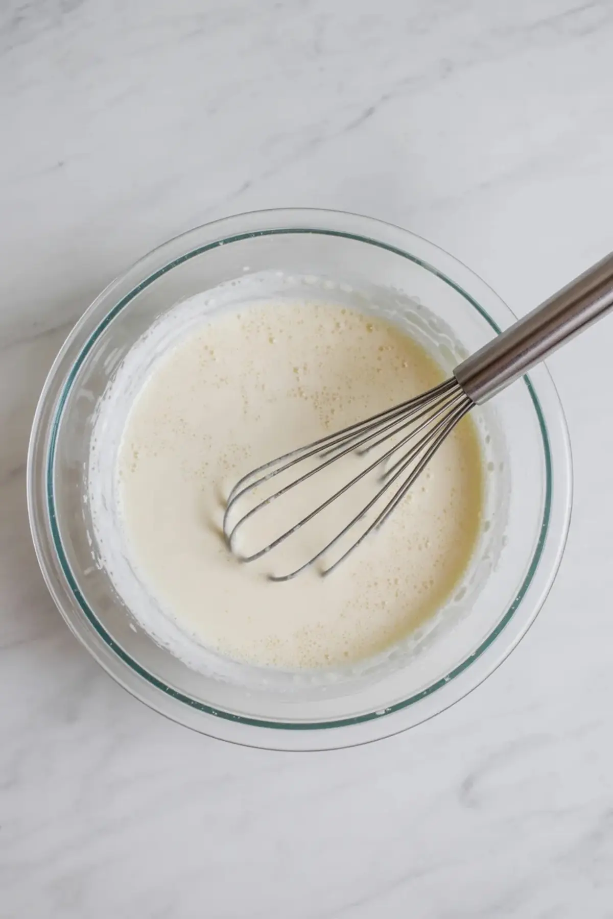 Cream and sugar mixture is whisked in a glass bowl to start this homemade cotton candy ice cream recipe and no churn ice cream base.