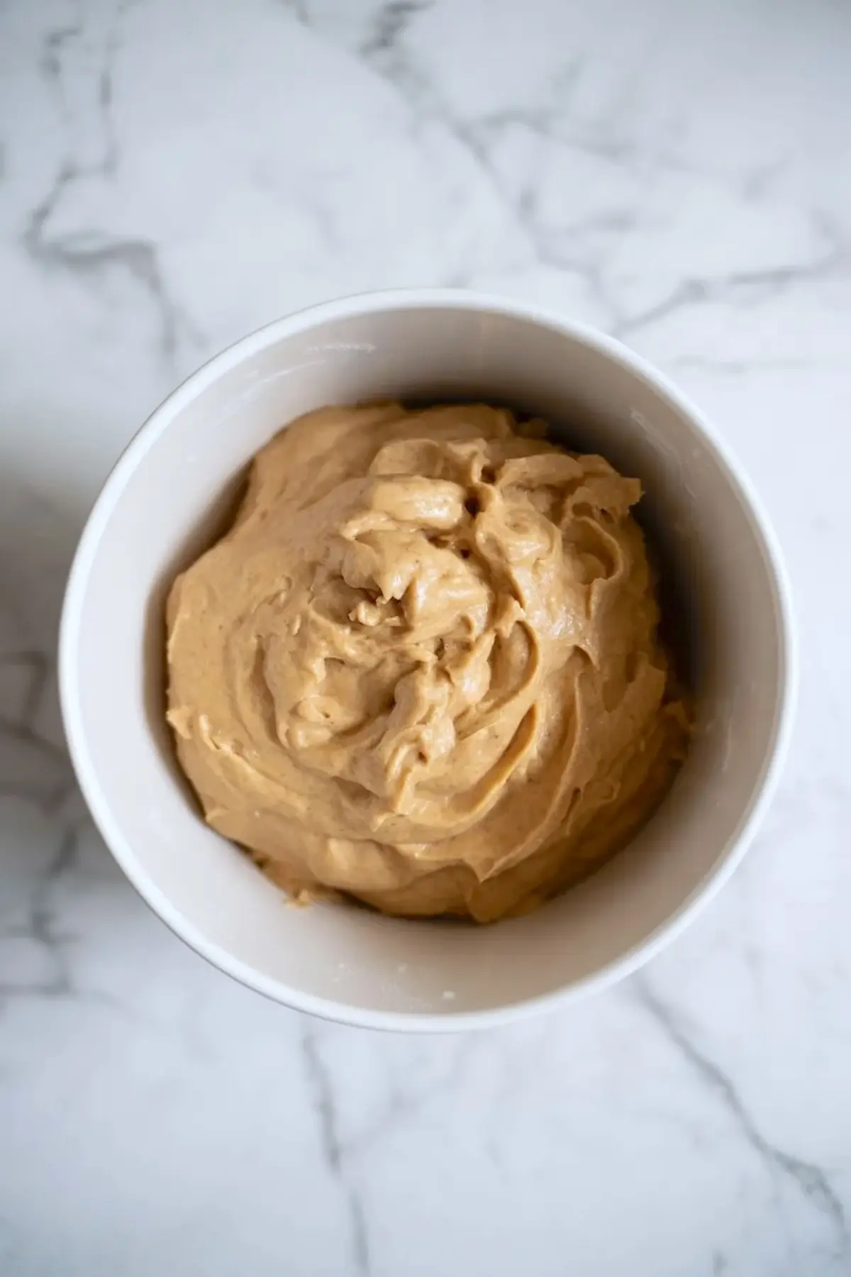 Soft espresso sour cream cookie dough in a white bowl, showing the smooth light coffee colored texture before scooping.