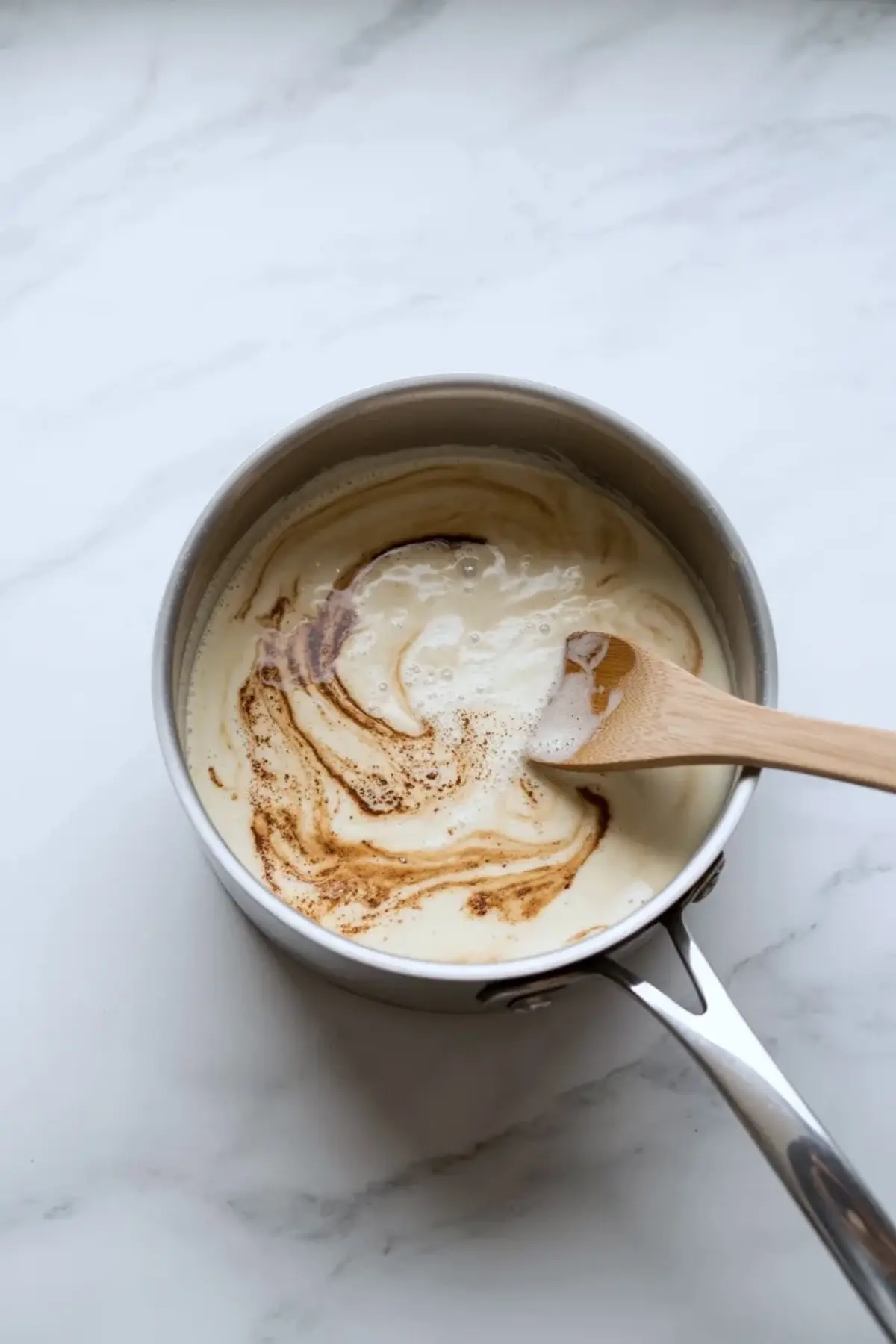 Coffee being whisked into the ice cream base in a saucepan or mixing bowl.