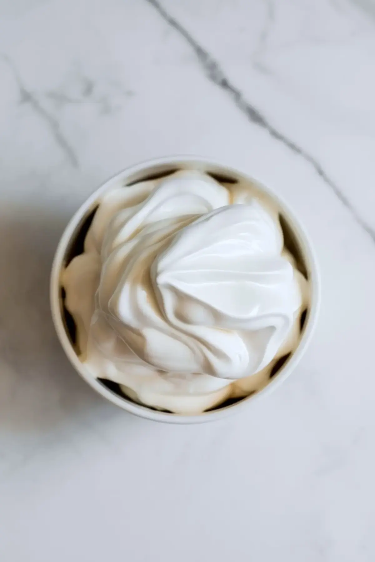 Glossy meringue for mini coconut cream pies swirled in a bowl before it is piped and toasted on top of the pies.