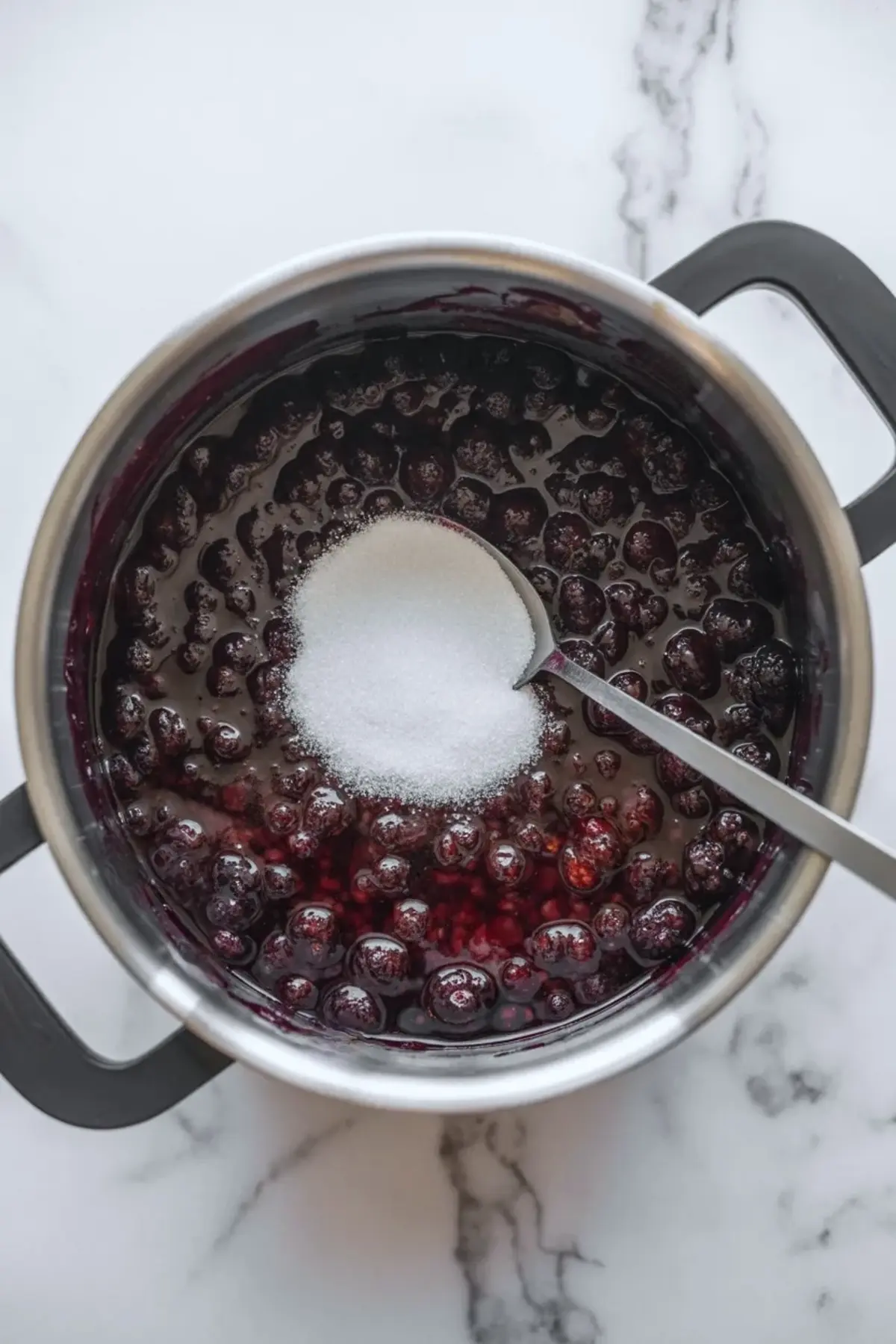 Finished mulberry jam sits in a jar with a spoon and glossy dark berry preserves that show a rich homemade jam texture.