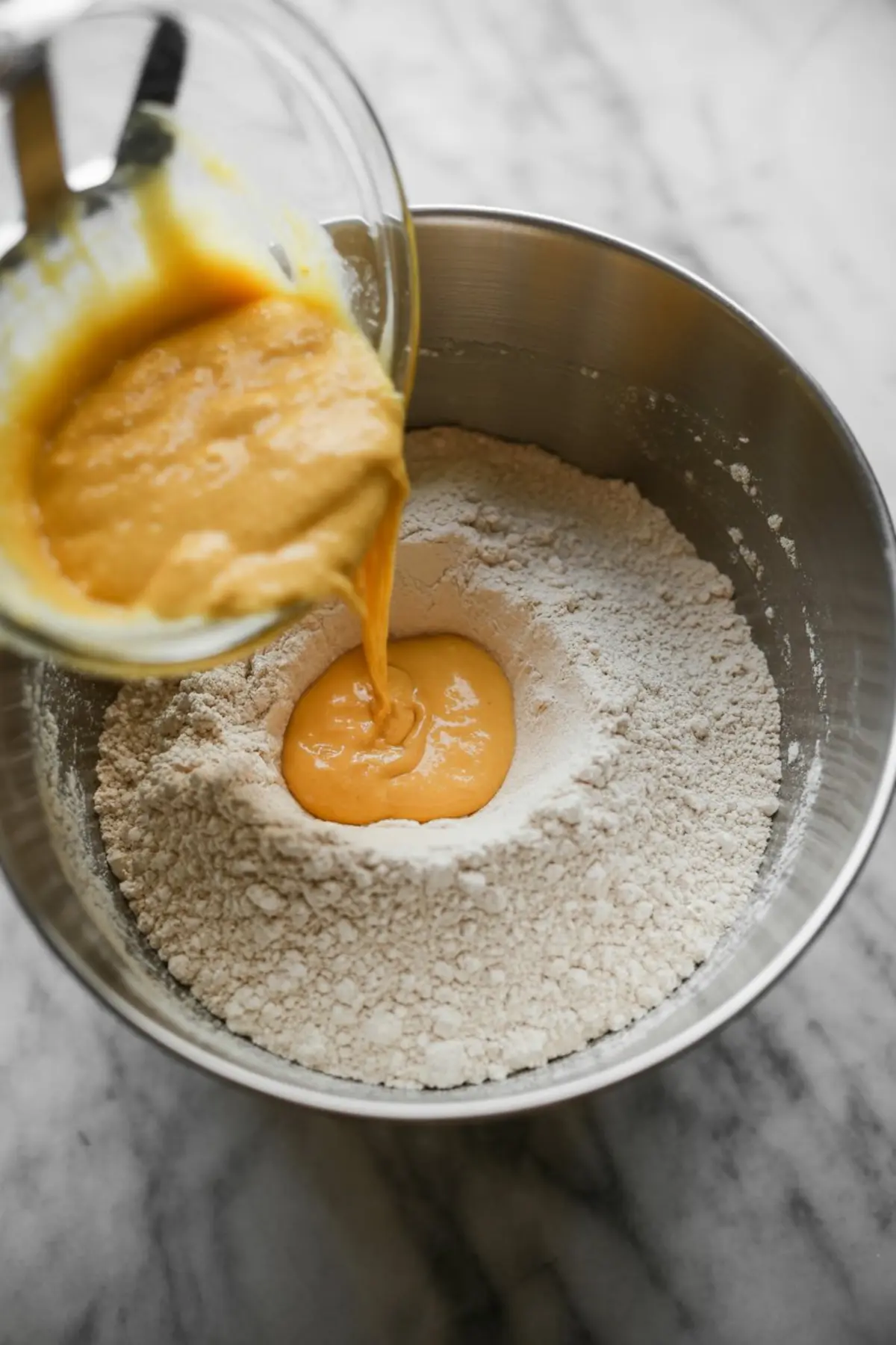 Orange juice and egg yolk mixture pours into the dry ingredients for orange chiffon cake batter.