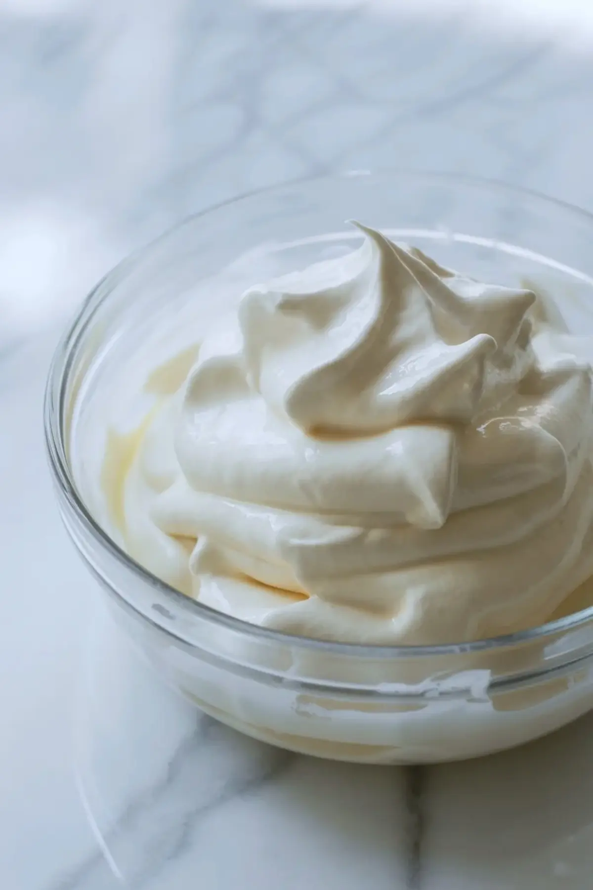 Soft whipped cream in a glass bowl, showing the airy stage that gives Oreo mousse its light texture.