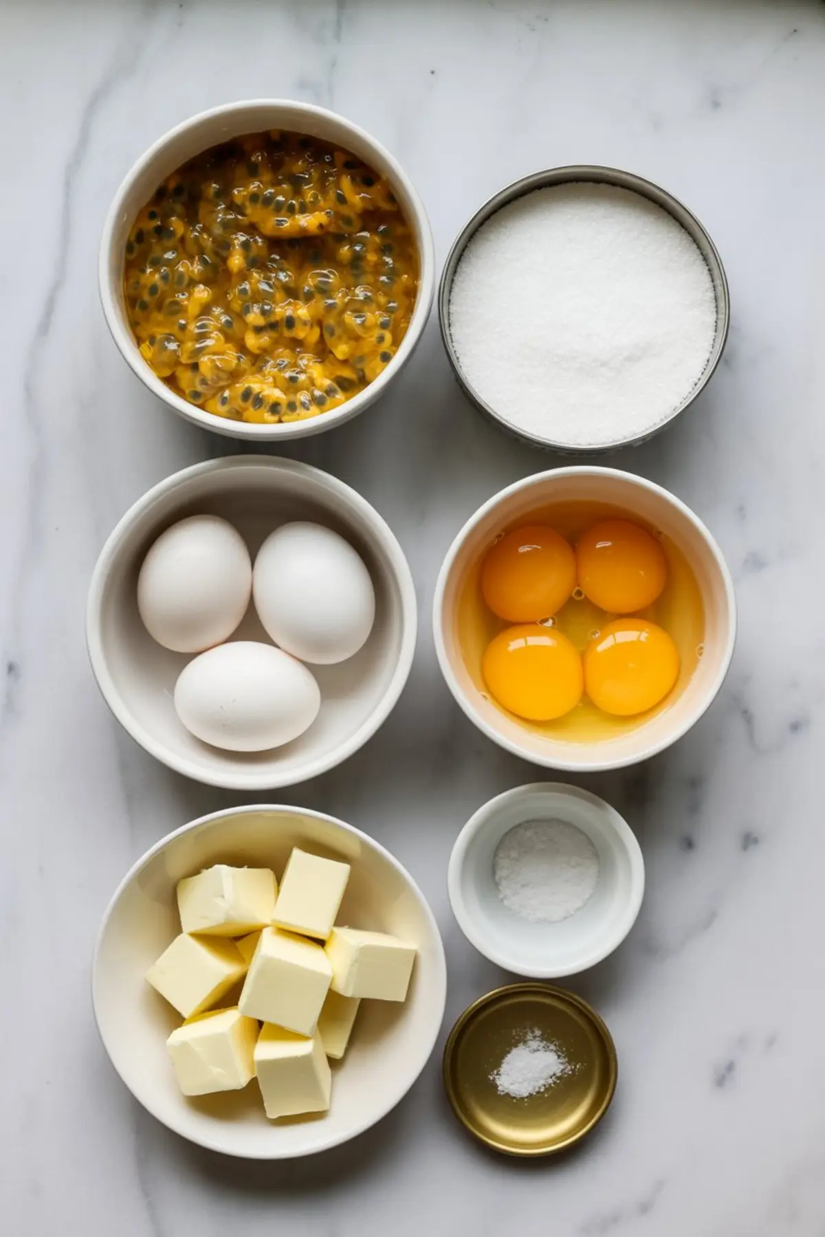 Passion fruit curd ingredients sit on a marble surface with eggs, sugar, butter, and passion fruit ready for a homemade fruit curd recipe.