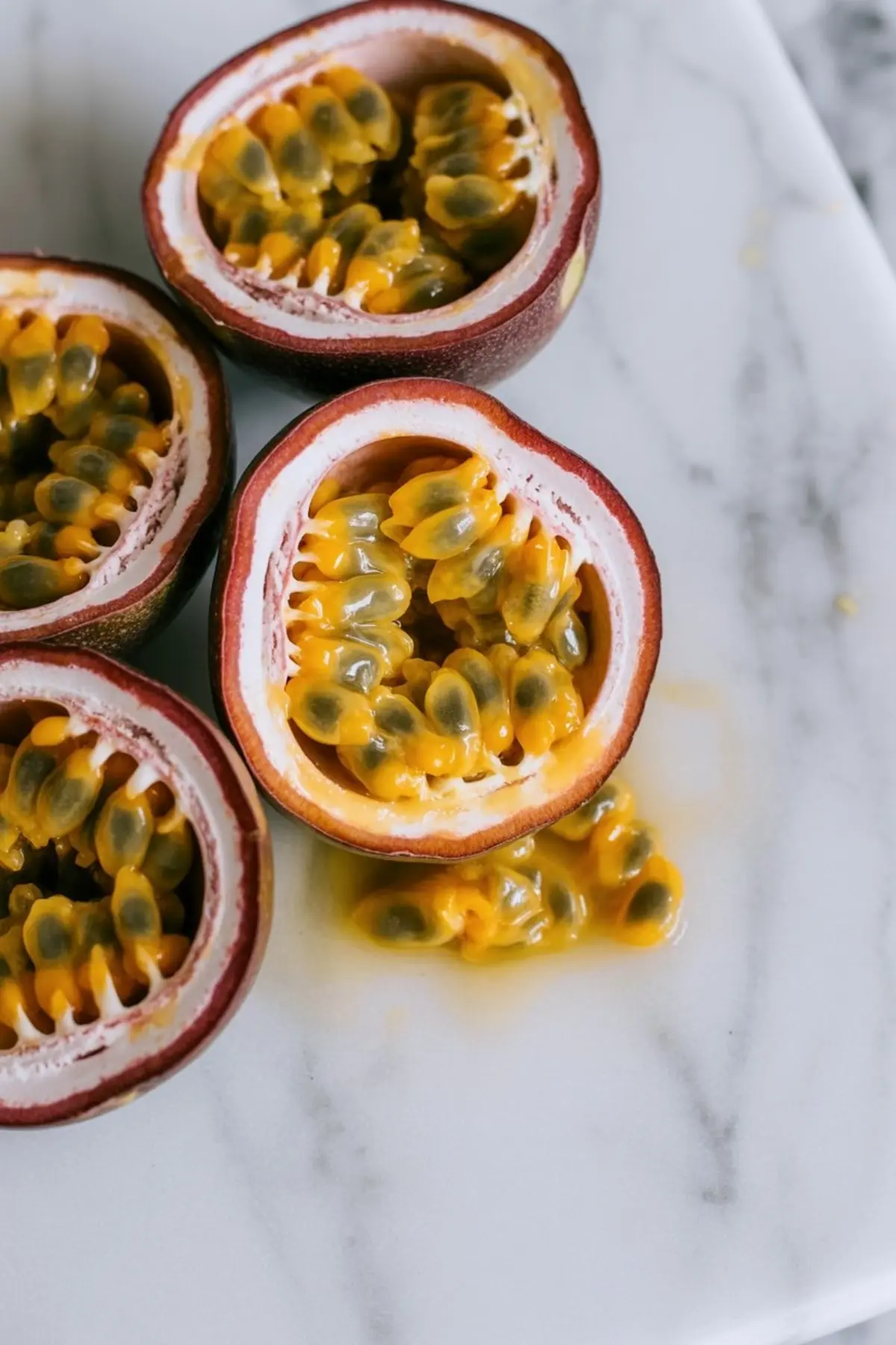 Fresh passion fruit halves sit in a bowl with their bright yellow pulp and black seeds ready for passion fruit curd.