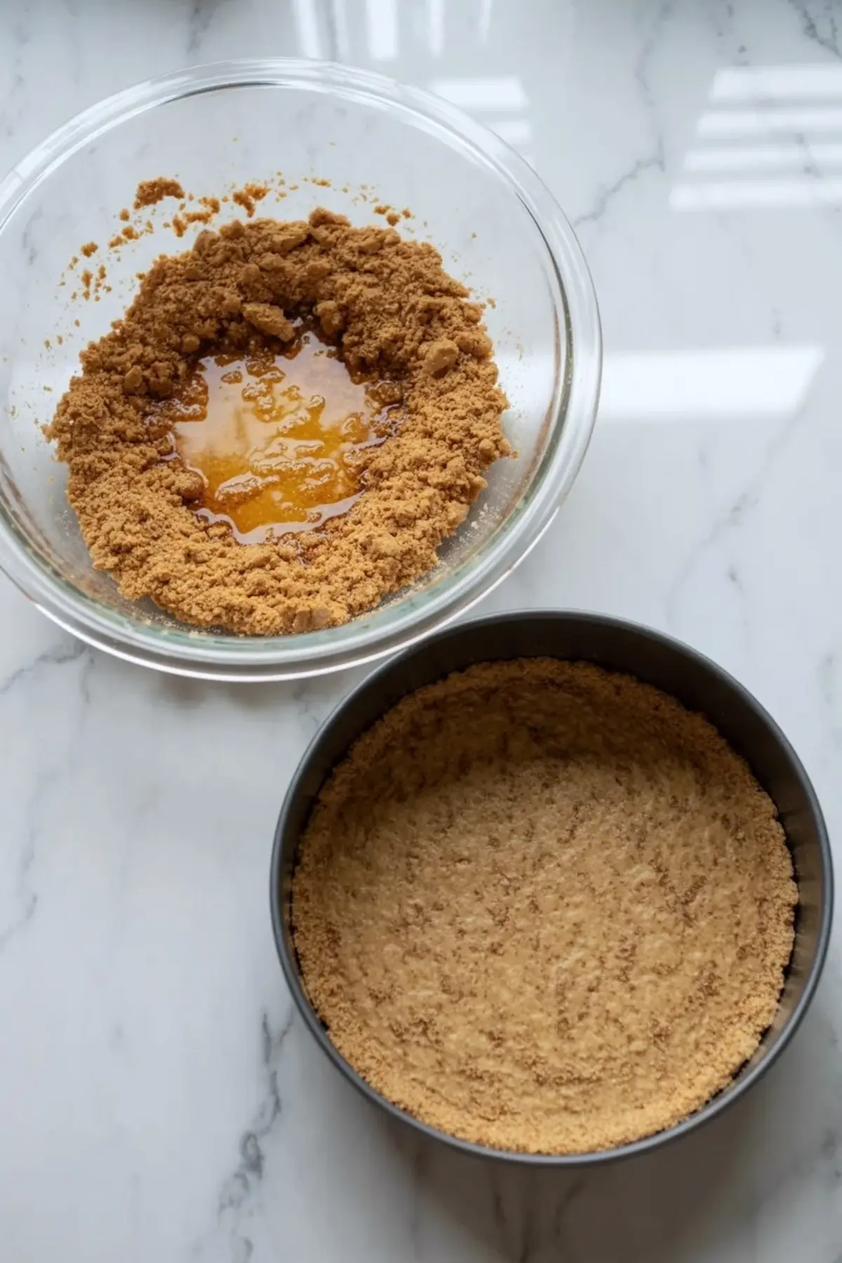 Graham cracker crust mixture with melted butter beside a springform pan crust for peach bourbon cobbler cheesecake.