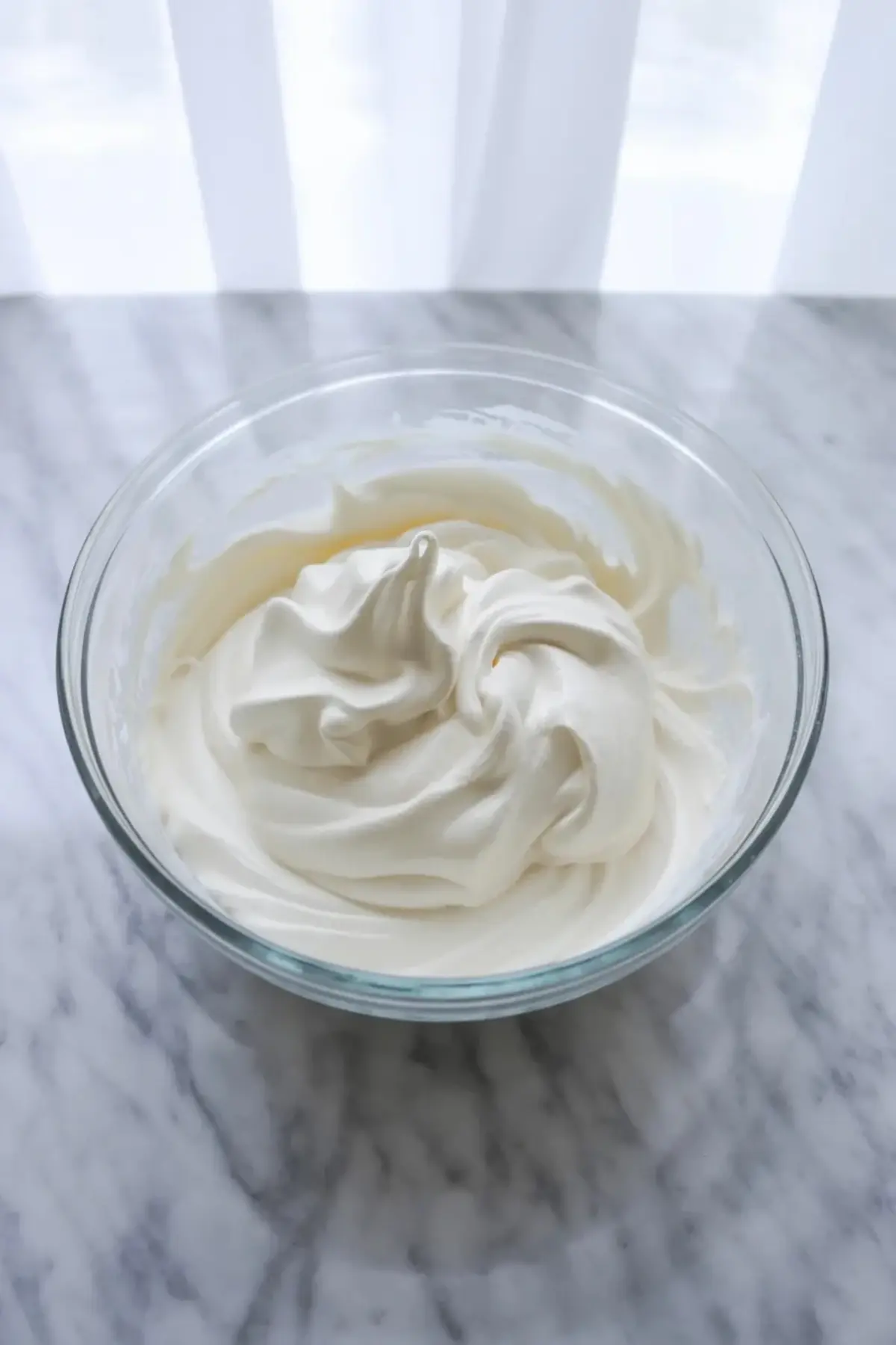 Peach cheesecake cup topped with peach slices and a spoonful lifted from the creamy cheesecake layer.