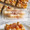 Honey-glazed peach crumble bar on a plate with glossy peach topping and crumb finish, shown from above on white marble.