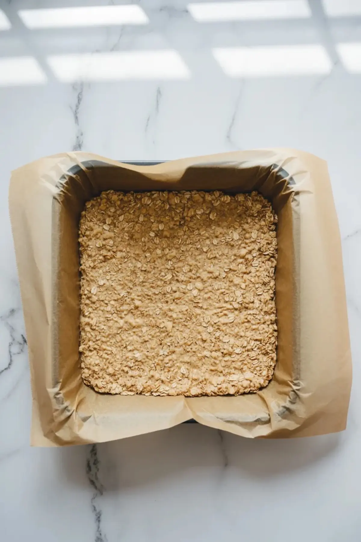 Close view of a peach crumble bar on a white plate showing the oat layers, soft peach filling, and vanilla glaze.