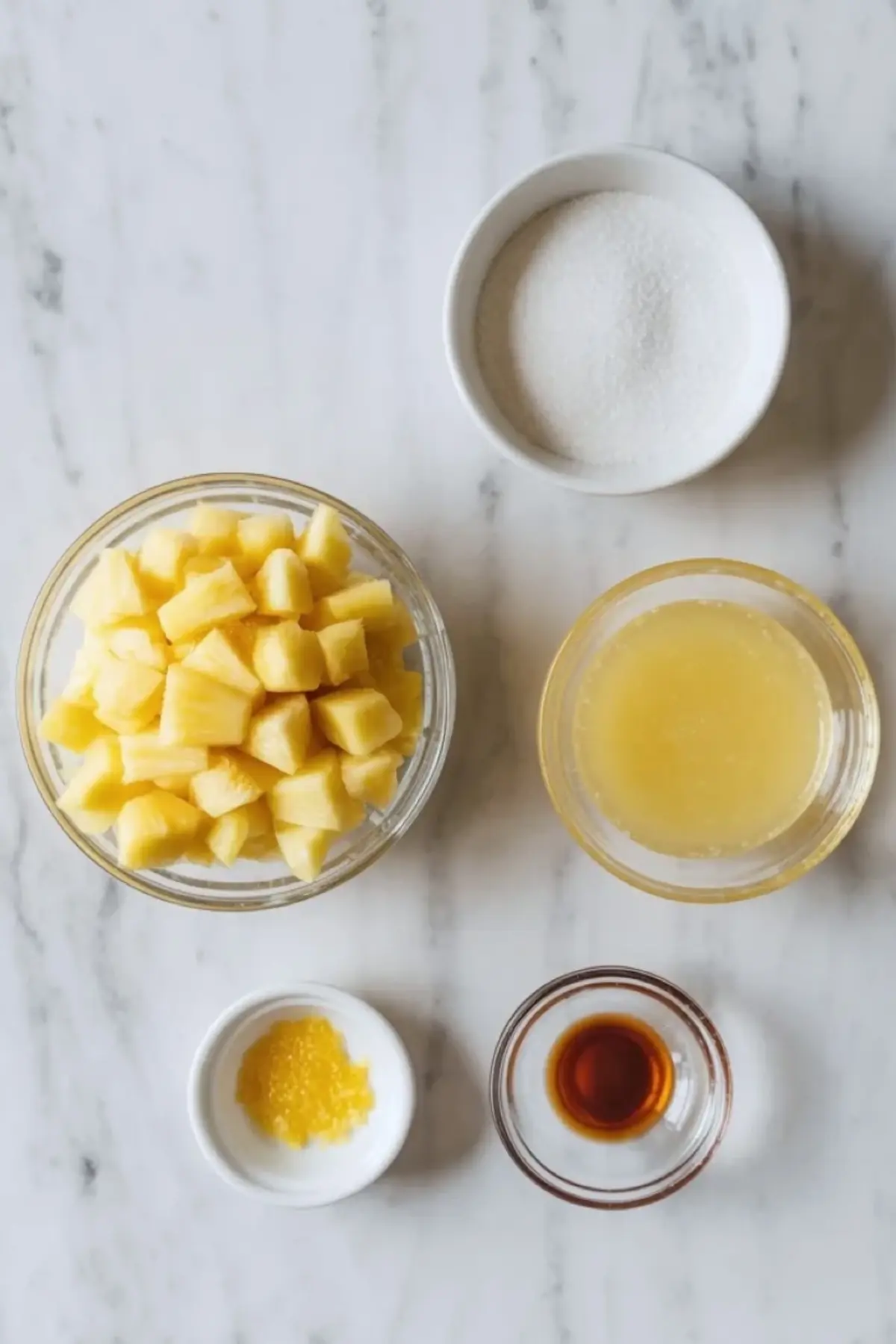 Jar of pineapple jam beside a spoon showing the chunky glossy fruit preserve.