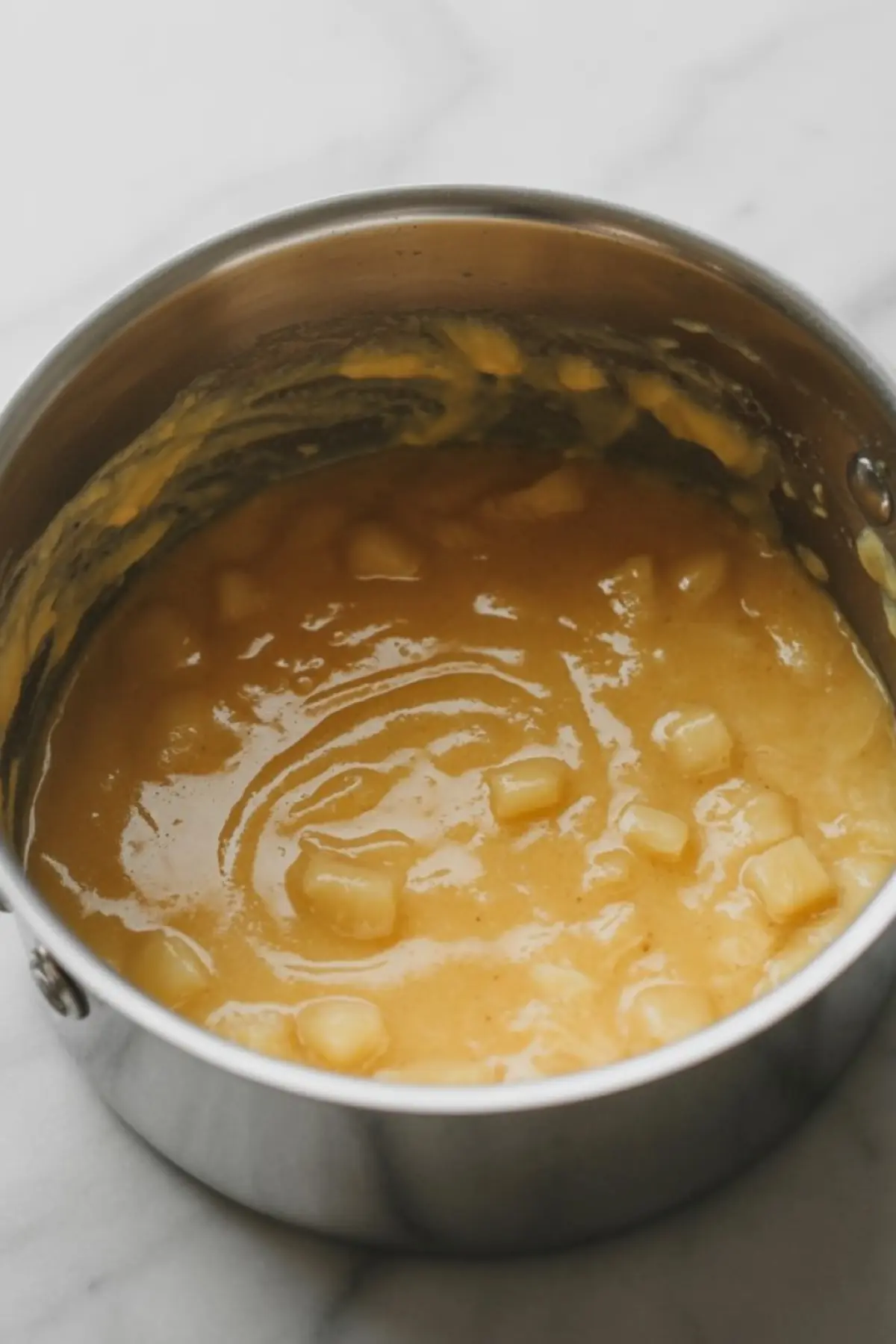 Pineapple cake filling sits in a bowl with a spoon, showing the soft glossy fruit texture for cakes, cupcakes, and layered desserts.