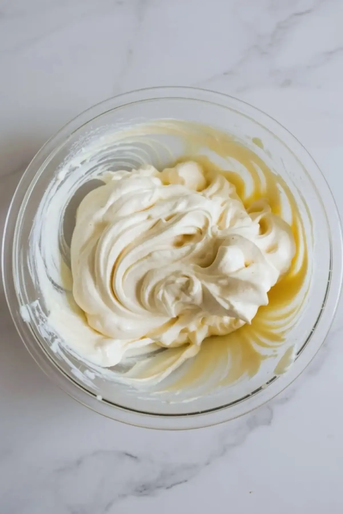 Creamy whipped base for strawberry pretzel fluff swirled in a glass bowl after the cream cheese mixture has been beaten smooth.