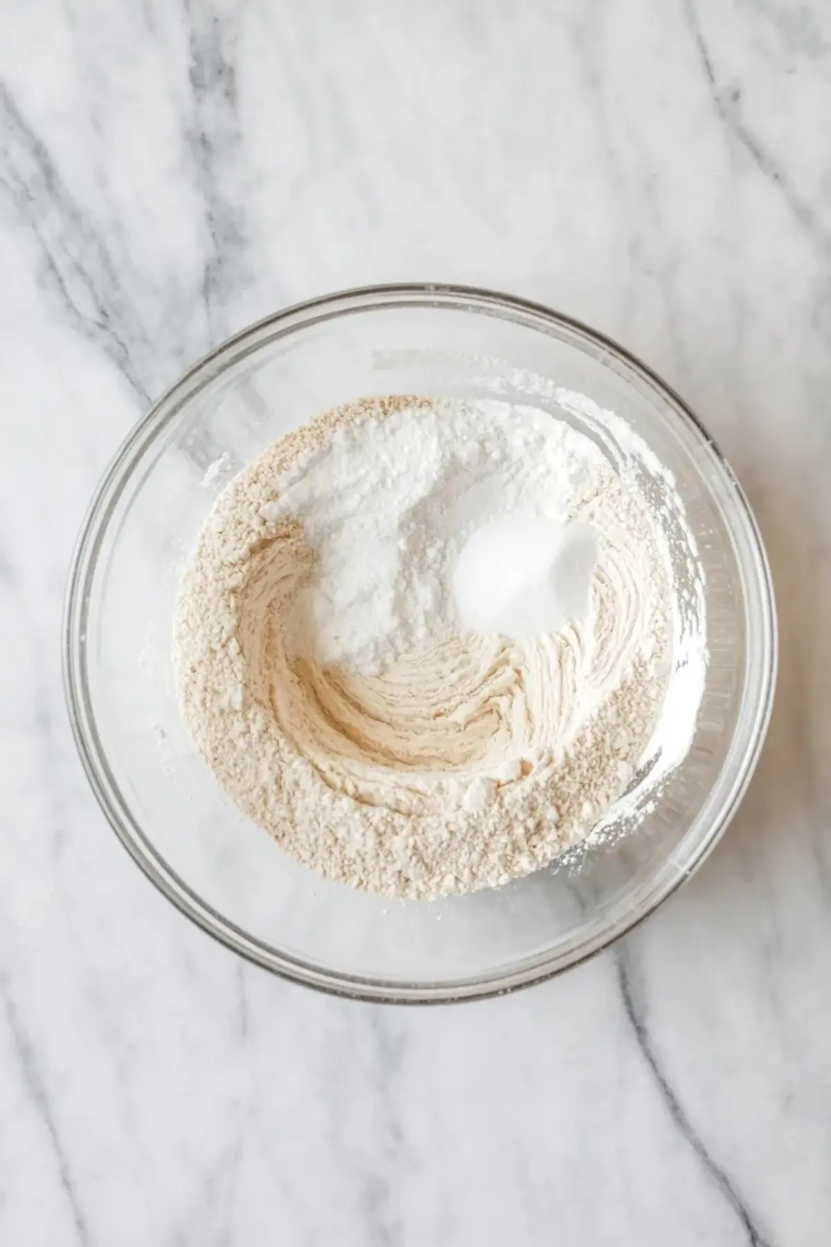 Ingredients for sheet pan strawberry shortcake cake arranged in a glass bowl and baking pan with strawberries, flour, butter, cream, and cake components on a white marble surface.