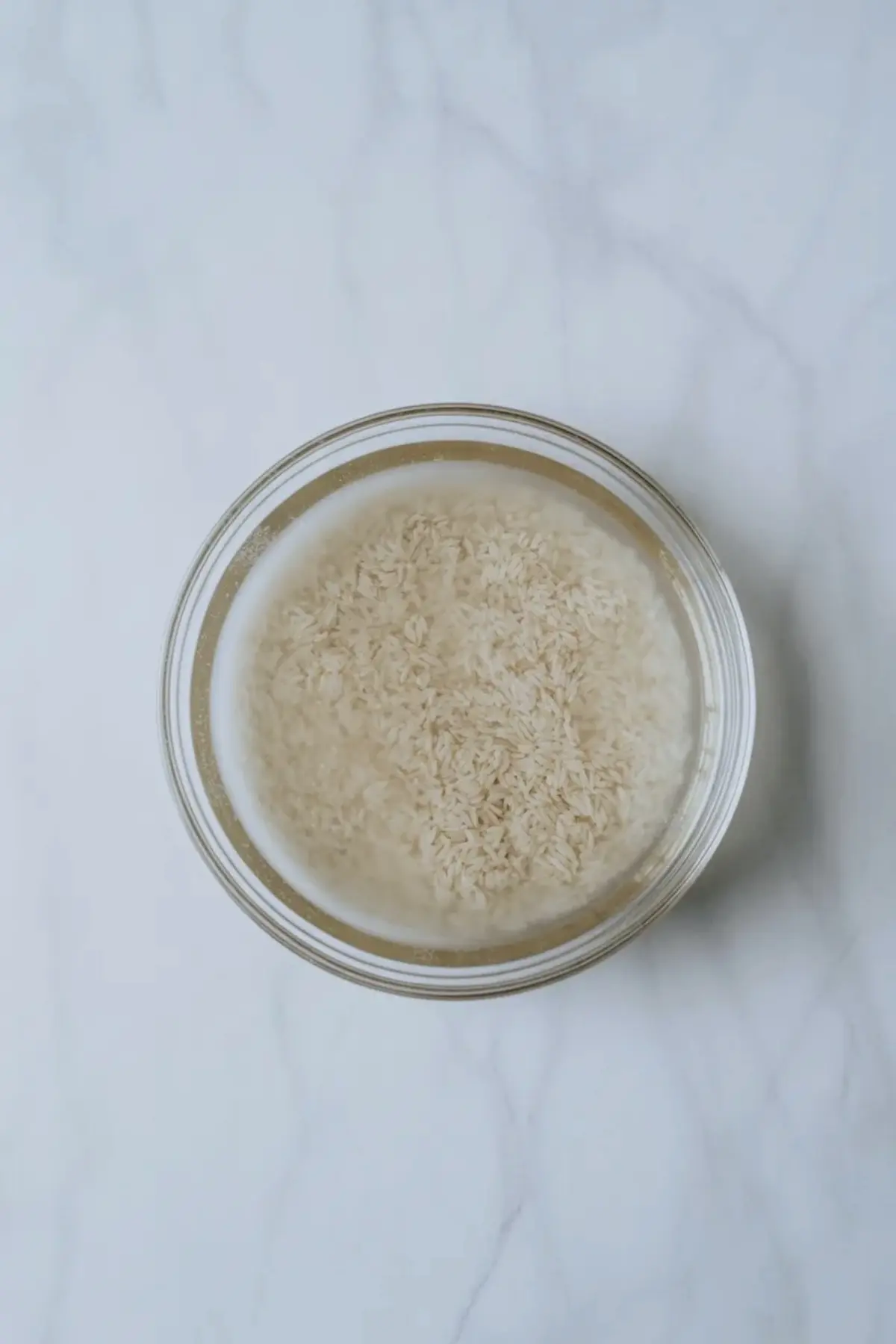 Short grain rice for vanilla poached pear rice pudding shown in a glass bowl before cooking.