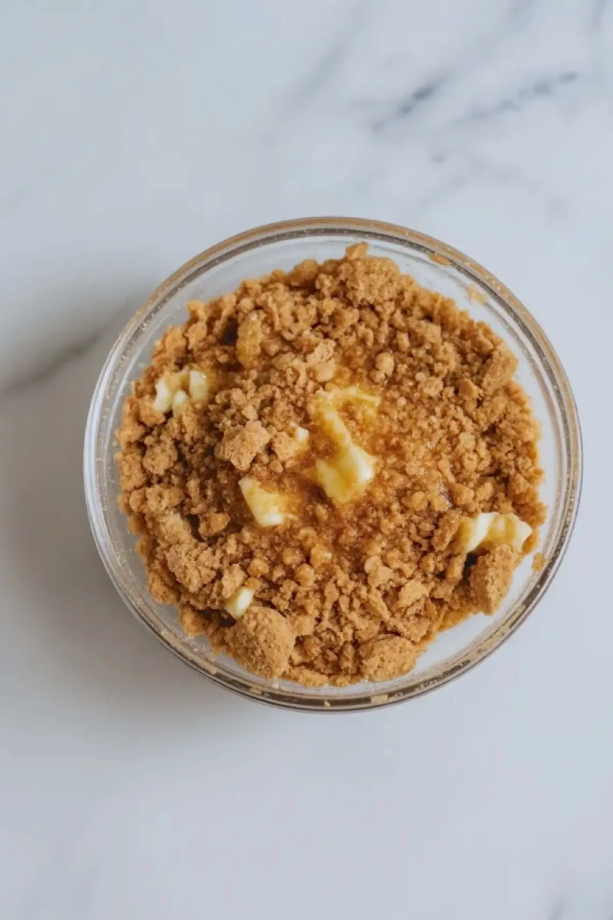 Chocolate cookie crumb crust mixture for banana split cheesecake bars sits in a small bowl before being pressed into the pan.
