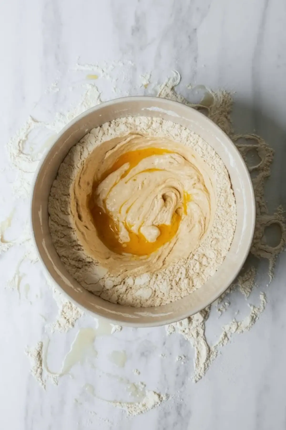 Donut dough mixing in a bowl with flour and egg, showing the early stage of the berry cream donuts dough coming together.