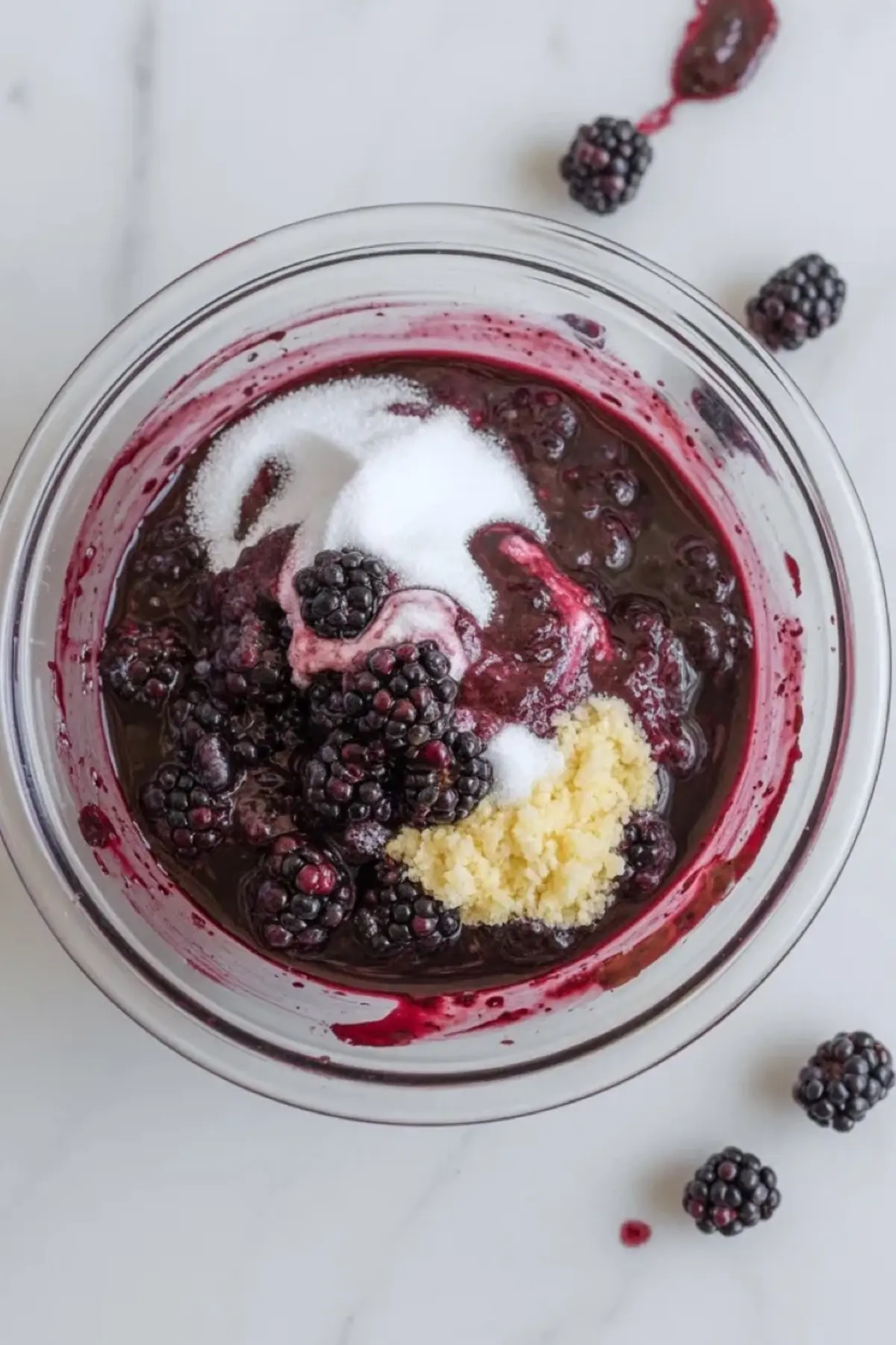 Blackberry crisp filling in a bowl with blackberries, sugar, lemon juice, and cornstarch before baking, showing the jammy fruit base in progress.