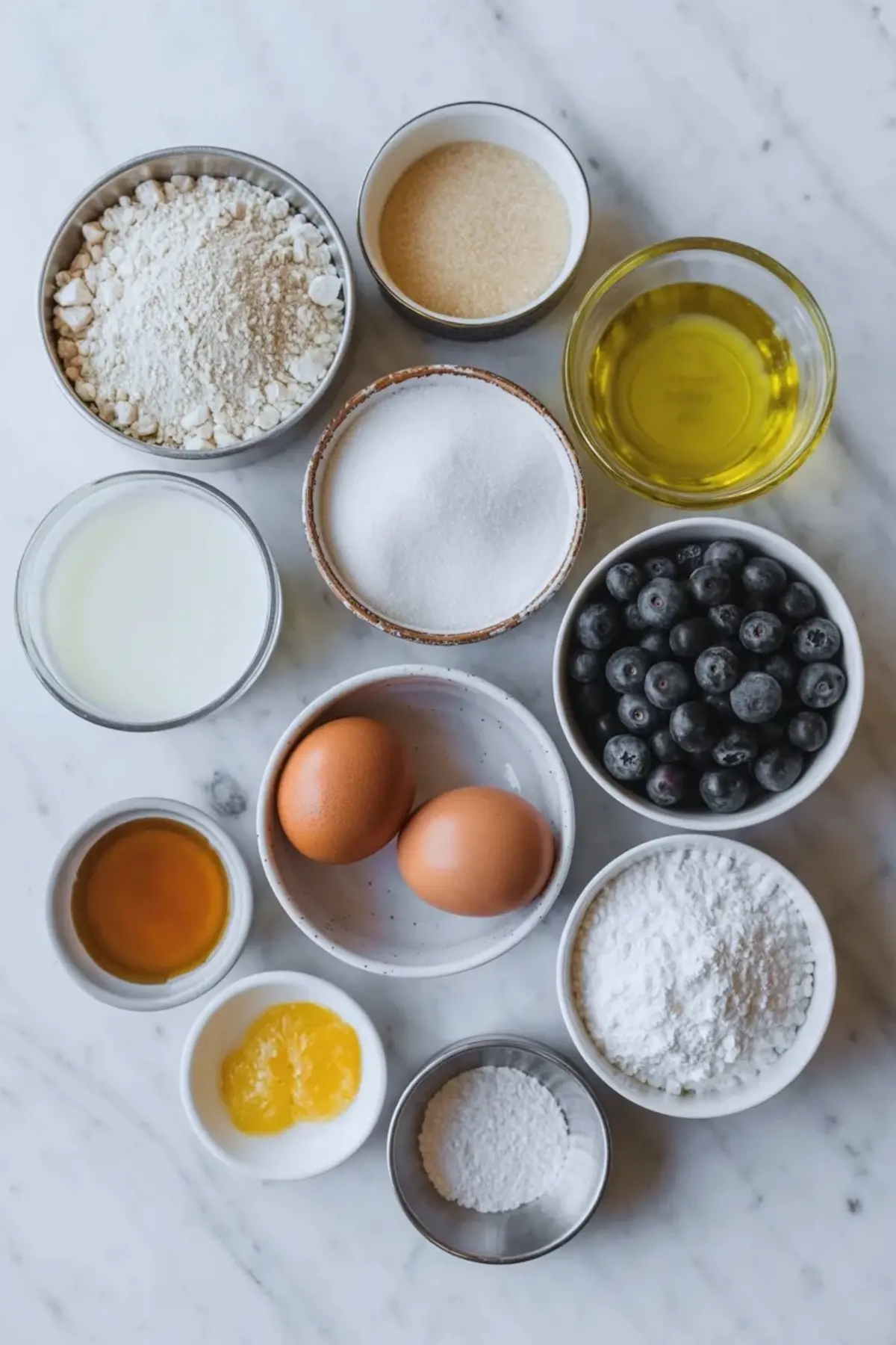 Ingredients for blueberry olive oil snack cake including flour, sugar, eggs, milk, olive oil, blueberries, lemon zest, vanilla, and powdered sugar.