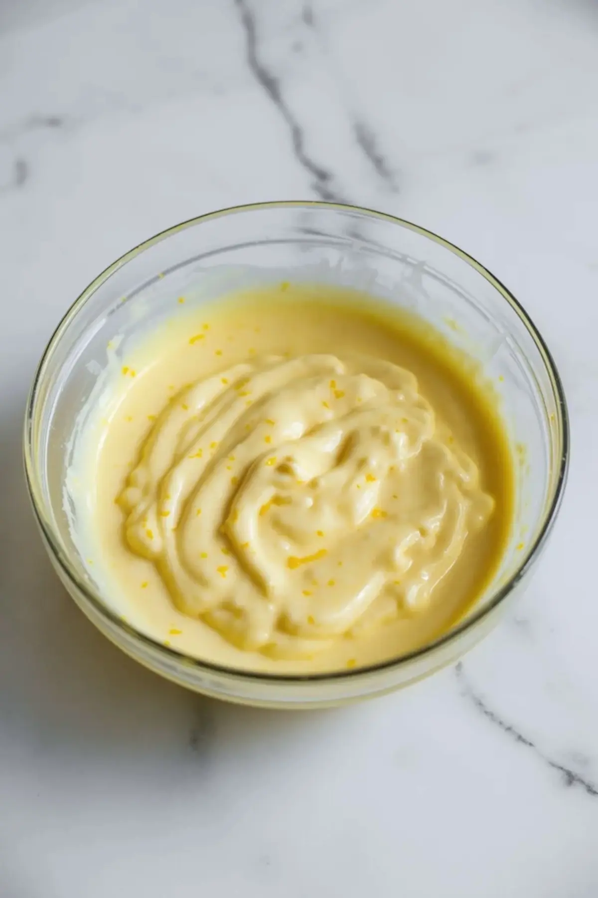 Smooth lemon filling in a glass bowl for brown butter lemon bars, showing the pale yellow citrus mixture before baking.