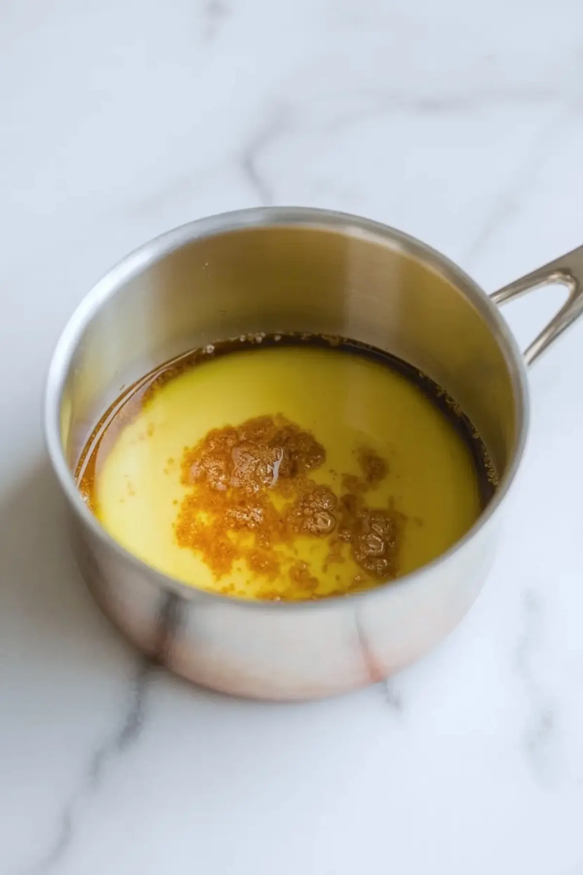 Browned butter in a saucepan for brown butter lemon bars, showing golden butter and toasted milk solids.