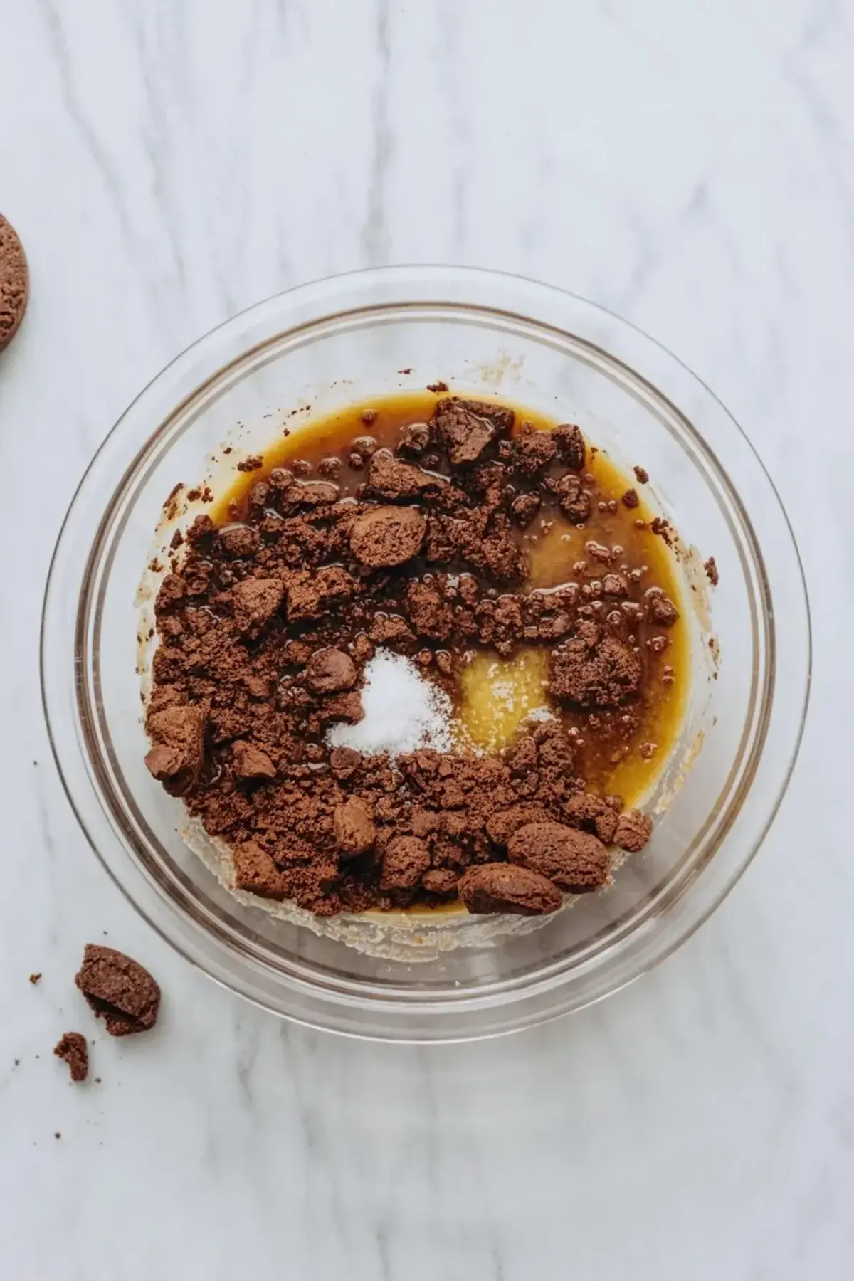 Chocolate crust mixture for chocolate vanilla cream pie bars in a glass bowl on a marble surface before pressing into the pan.