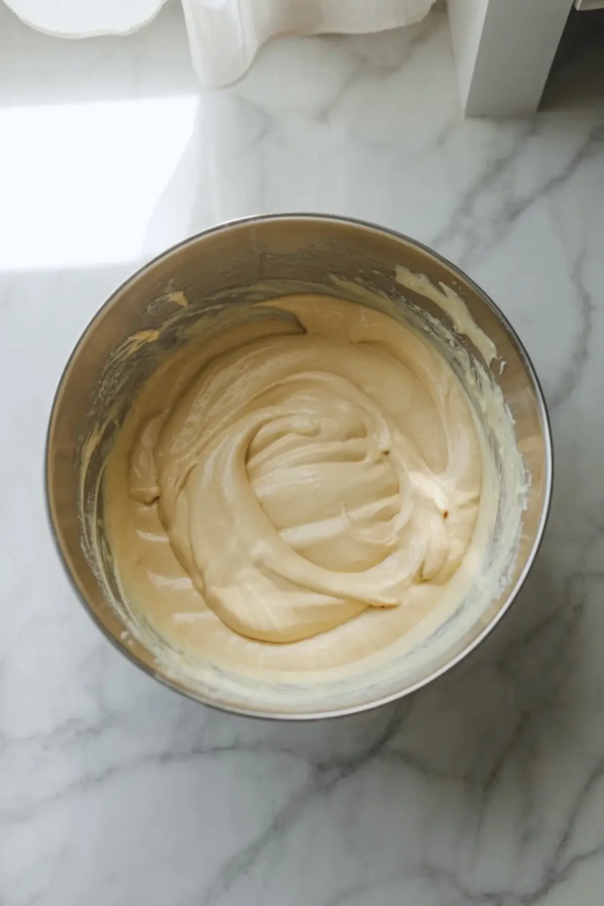 Smooth cheesecake filling in a mixing bowl, showing the creamy base before the peach cobbler cheesecake is assembled.