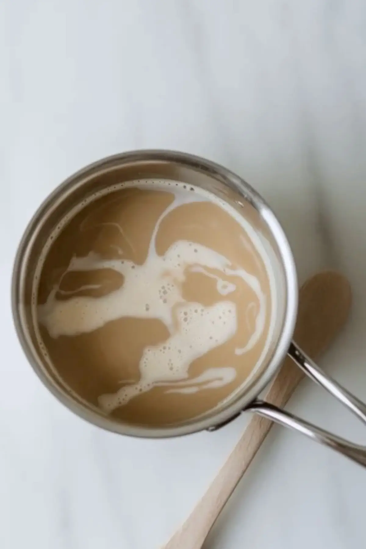 Espresso milk mixture in a saucepan for espresso cake filling, showing the coffee-infused milk before tempering the eggs.