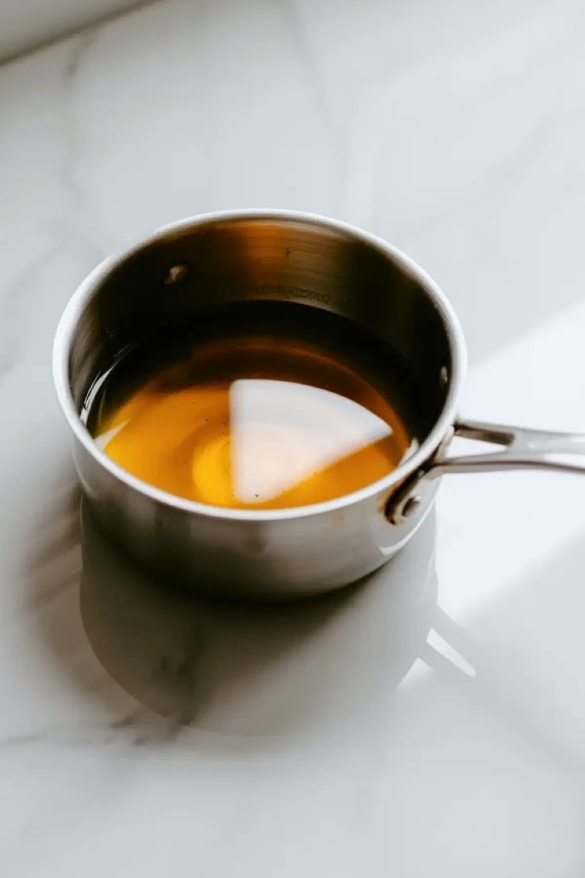 Smooth amber syrup in a saucepan for homemade amaretto after the sugars have dissolved.