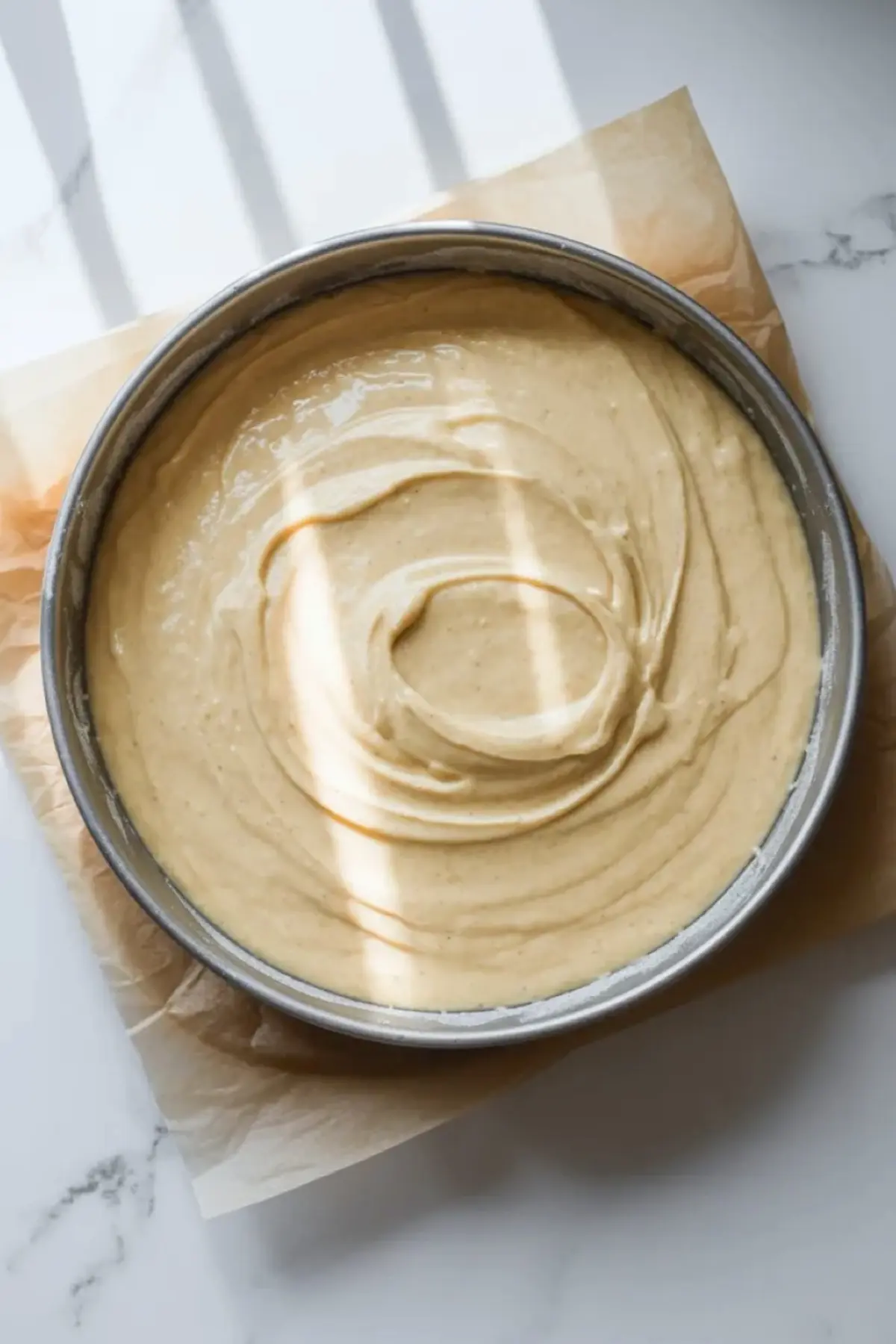 Mascarpone olive oil berry cake batter spread in a round cake pan before baking.