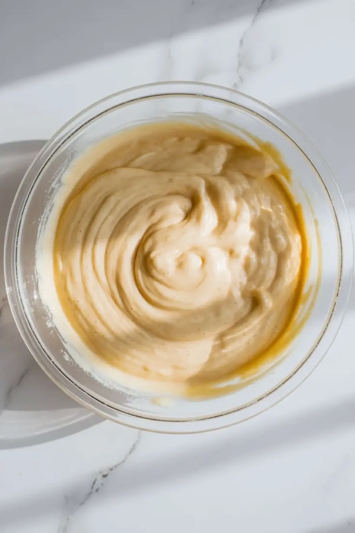 Smooth finished batter for mascarpone olive oil berry cake in a glass mixing bowl.