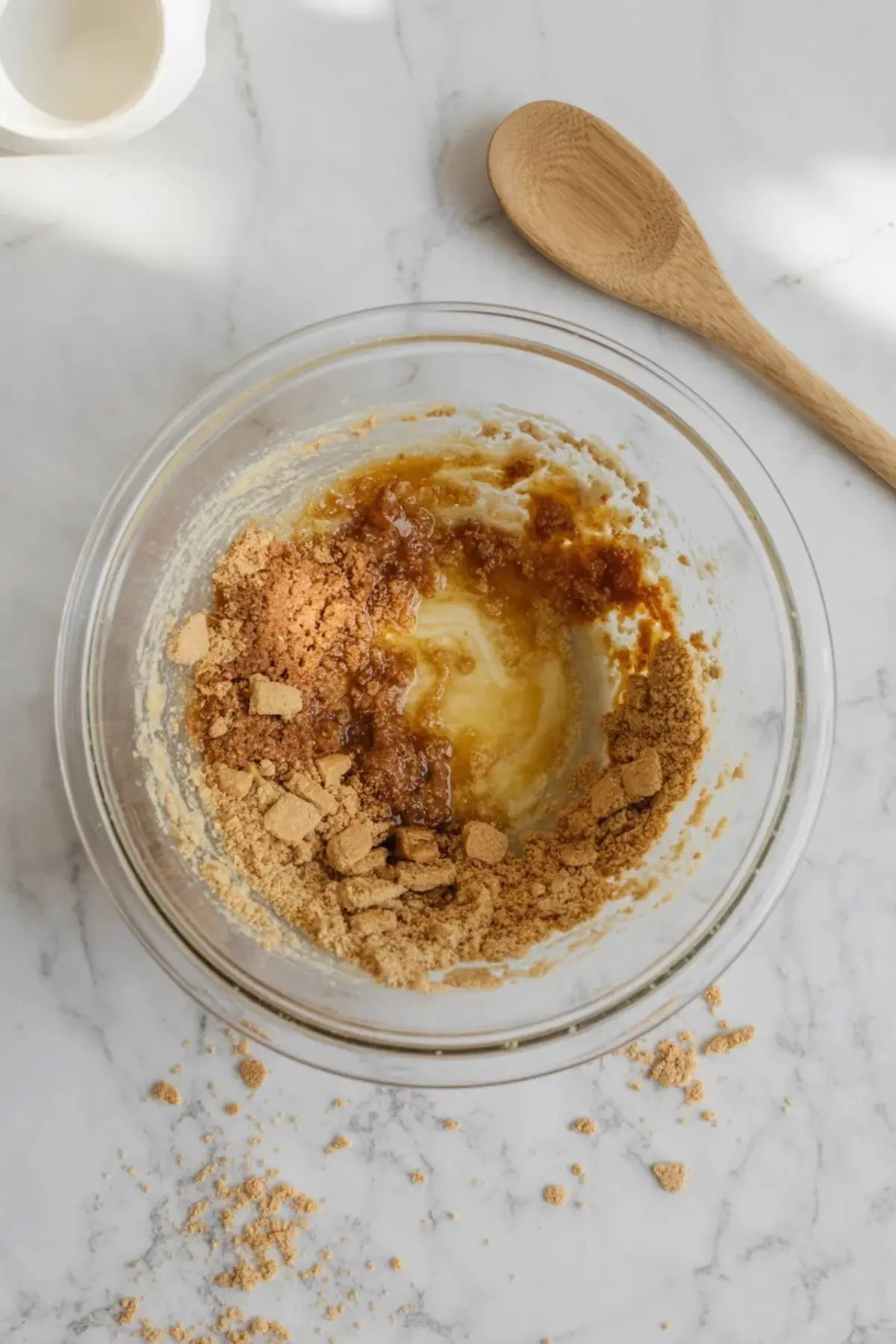 Crushed biscuits mixed with butter and brown sugar in a glass bowl for mini banana mousse cheesecakes before pressing into the crusts.