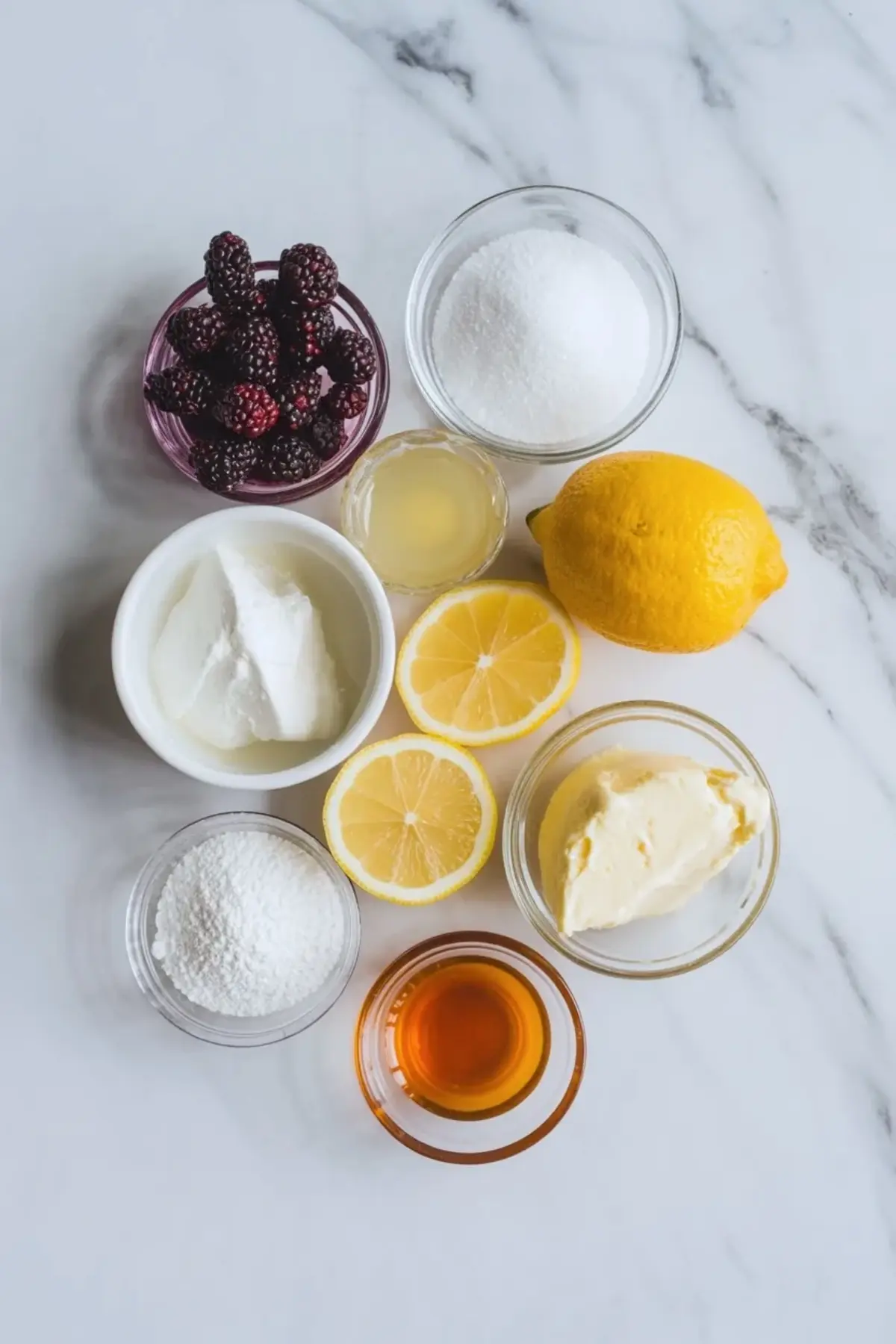 Ingredients for mulberry mousse cake filling arranged on a white marble surface with mulberries, sugar, lemon, cream cheese, powdered sugar, and vanilla.