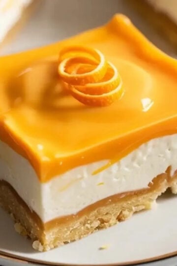 Featured orange creamsicle bars image showing one sliced bar on a plate with glossy orange topping, creamy white filling, and buttery graham crust.
