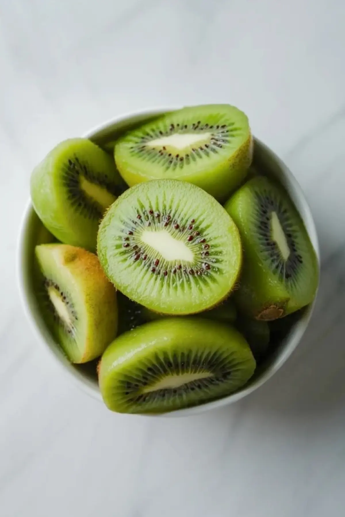 Fresh kiwi halves in a white bowl for papaya lime boats, showing one of the bright fruit toppings used in the filling.