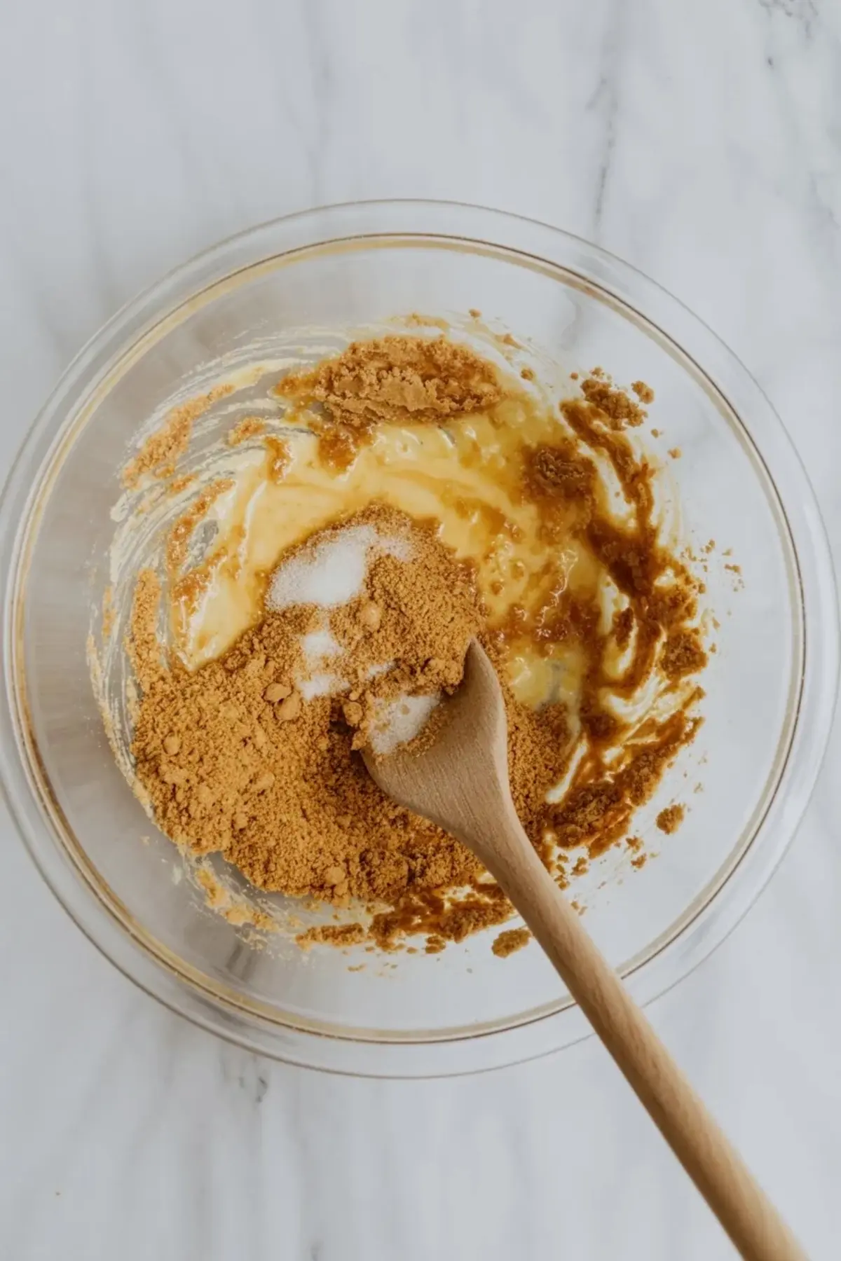 Graham cracker crumbs, butter, and sugar being mixed in a bowl for the patriotic lemon icebox pie crust.