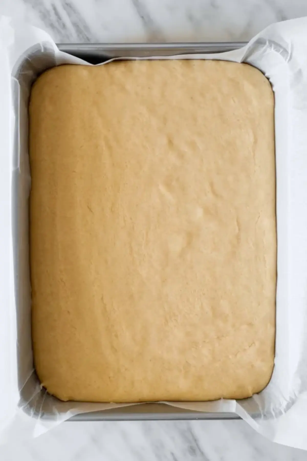 Baked sugar cookie bar base in a lined pan before frosting for patriotic sugar cookie bars.