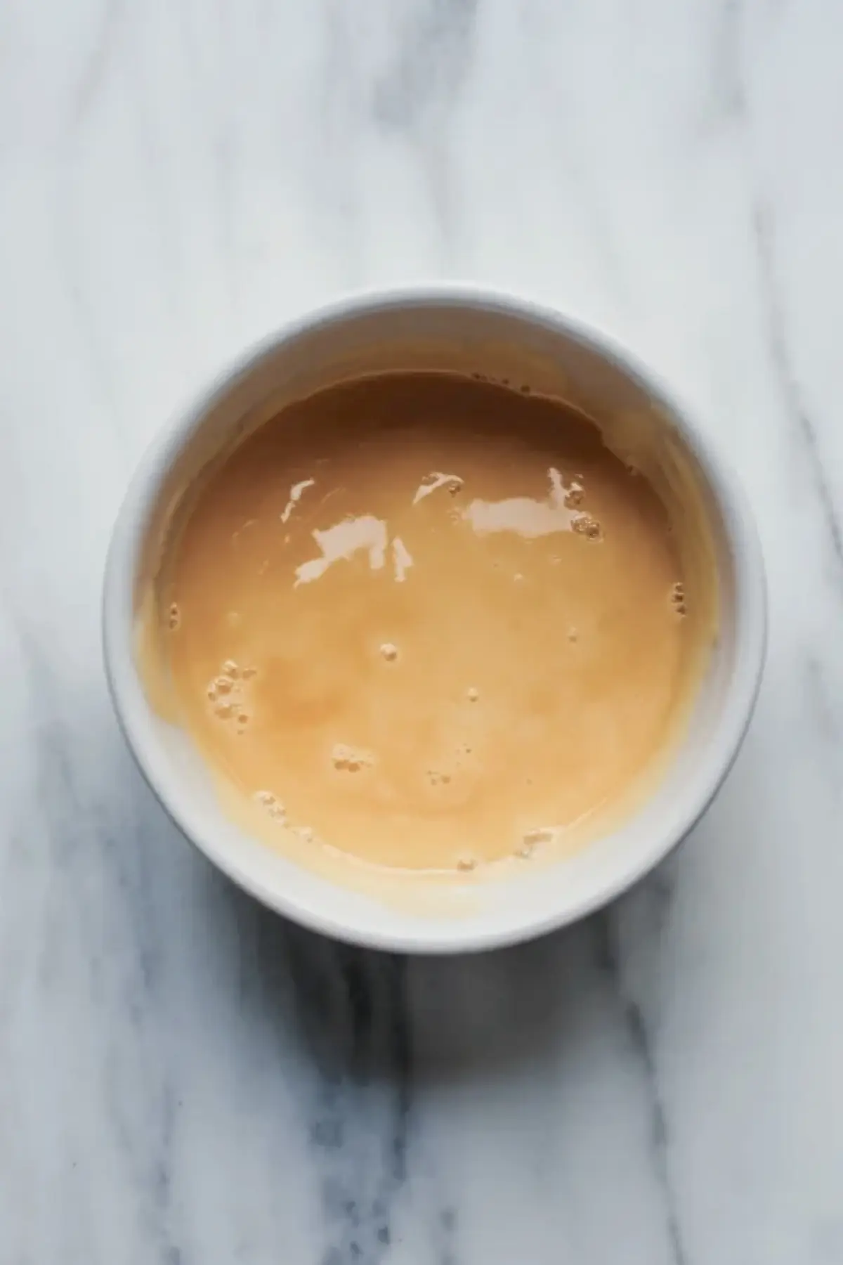 Simple glaze in a small bowl, showing the icing used to finish the peach danishes.