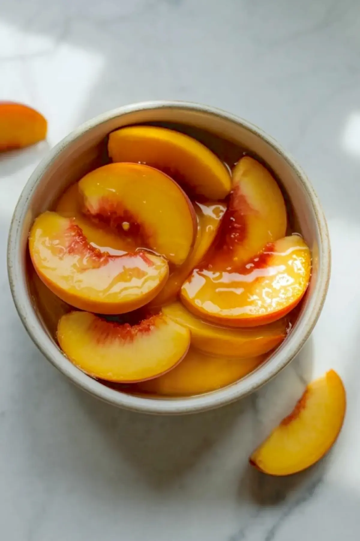 Peach slices in syrup or glaze in a bowl, showing the fruit topping for the danishes before assembly.