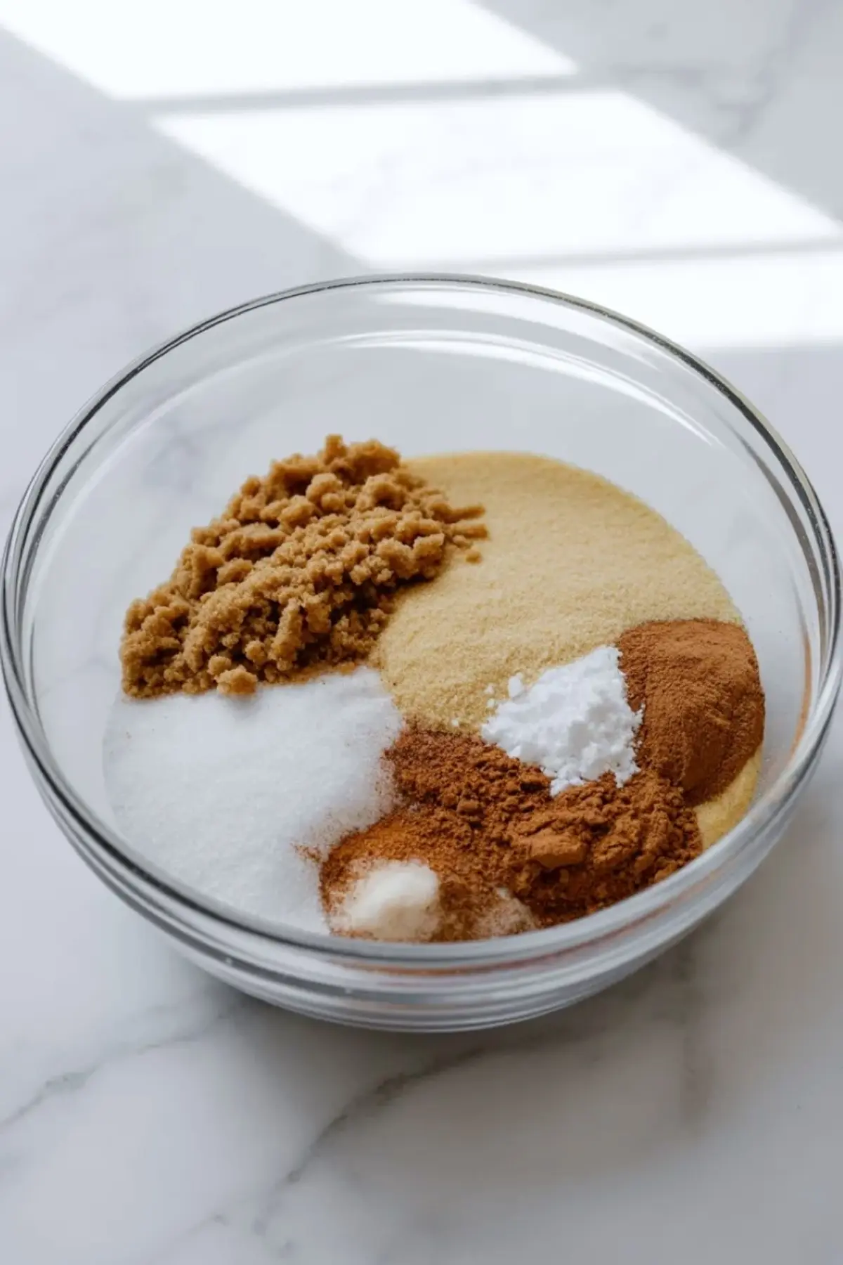 Sugar, brown sugar, cinnamon, and thickener measured in a bowl for pear pie filling.
