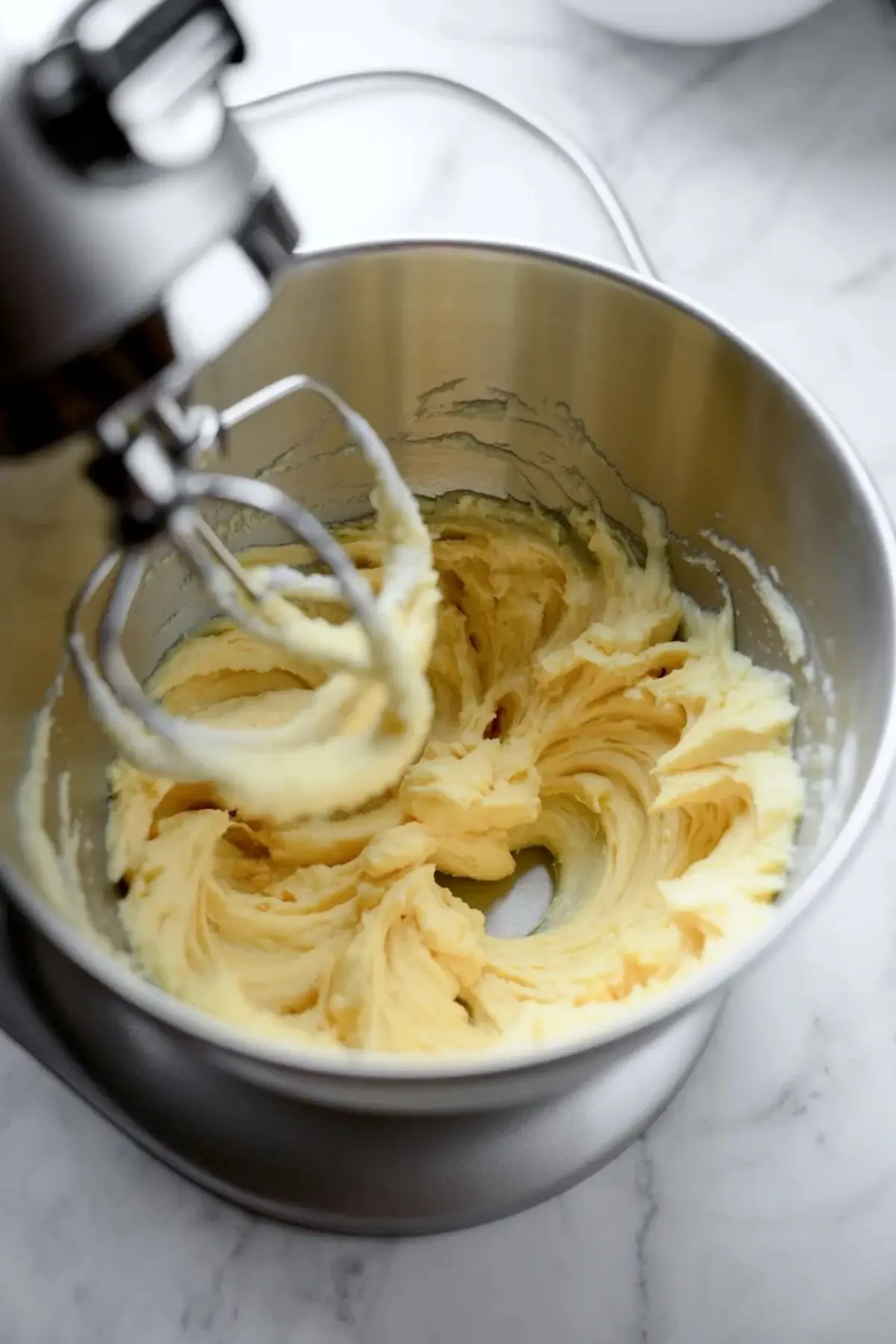 Butter and sugar creamed in a stand mixer for snickerdoodle bundt cake, showing the pale fluffy base before the eggs and sour cream are added.