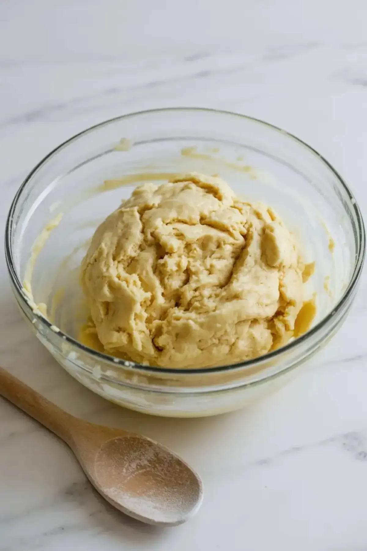 Fresh strawberry filling for strawberry pie bars in a white bowl with sliced strawberries and glossy juices on a marble surface.