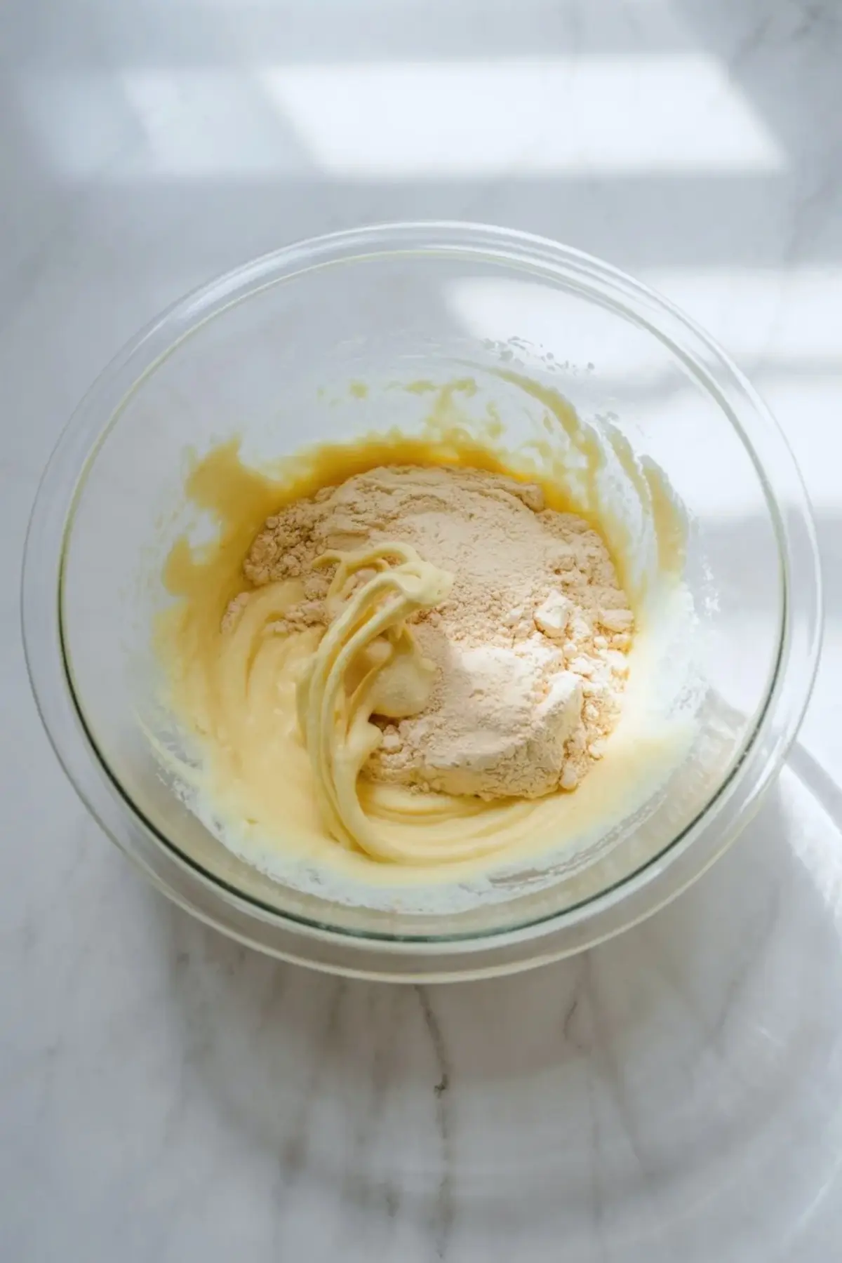 Vanilla pudding base for strawberry shortcake fluff salad is being mixed in a glass bowl as the dry pudding thickens the creamy base.