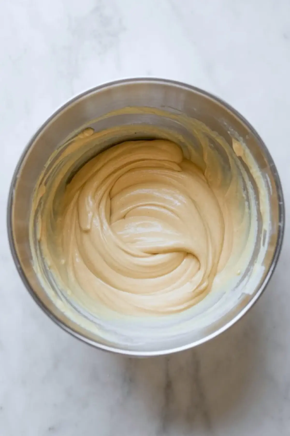 Smooth American flag cake batter sits in the mixer bowl after the wet and dry ingredients have been fully combined.