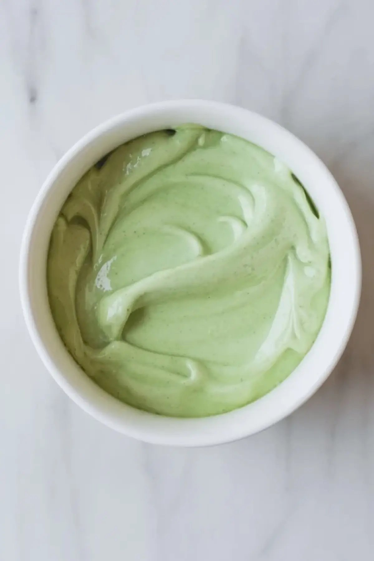 Smooth pale green mint filling for Andes mint brownies in a white bowl, showing the creamy texture before it is spread over the cooled brownies.