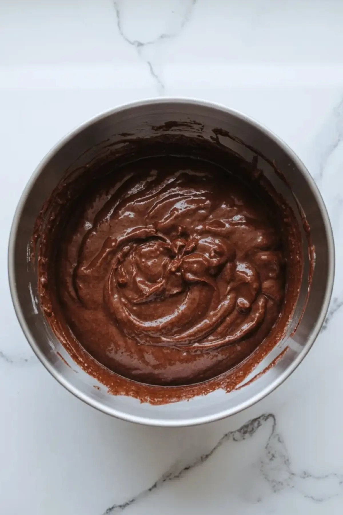 Chocolate brownie batter in a mixing bowl, showing the thick glossy texture before it is spread into the pan for Andes mint brownies.