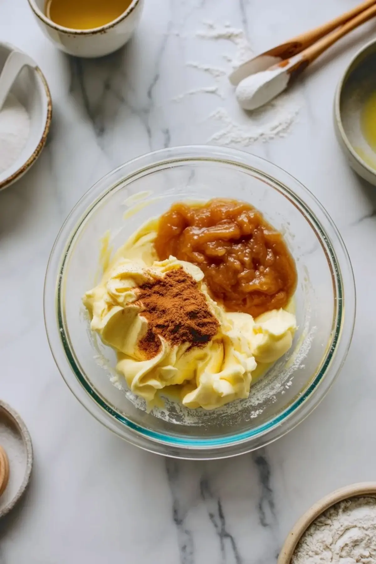Apple butter frosting ingredients in a mixing bowl with butter, apple butter, cinnamon, and powdered sugar during the frosting process.