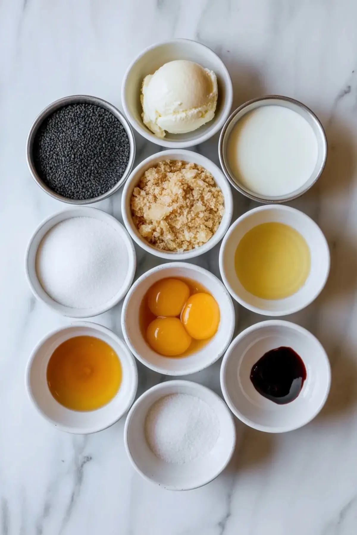 Ingredients for black sesame ice cream are arranged in bowls with black sesame seeds, cream, milk, egg yolks, sugar, honey, and vanilla.