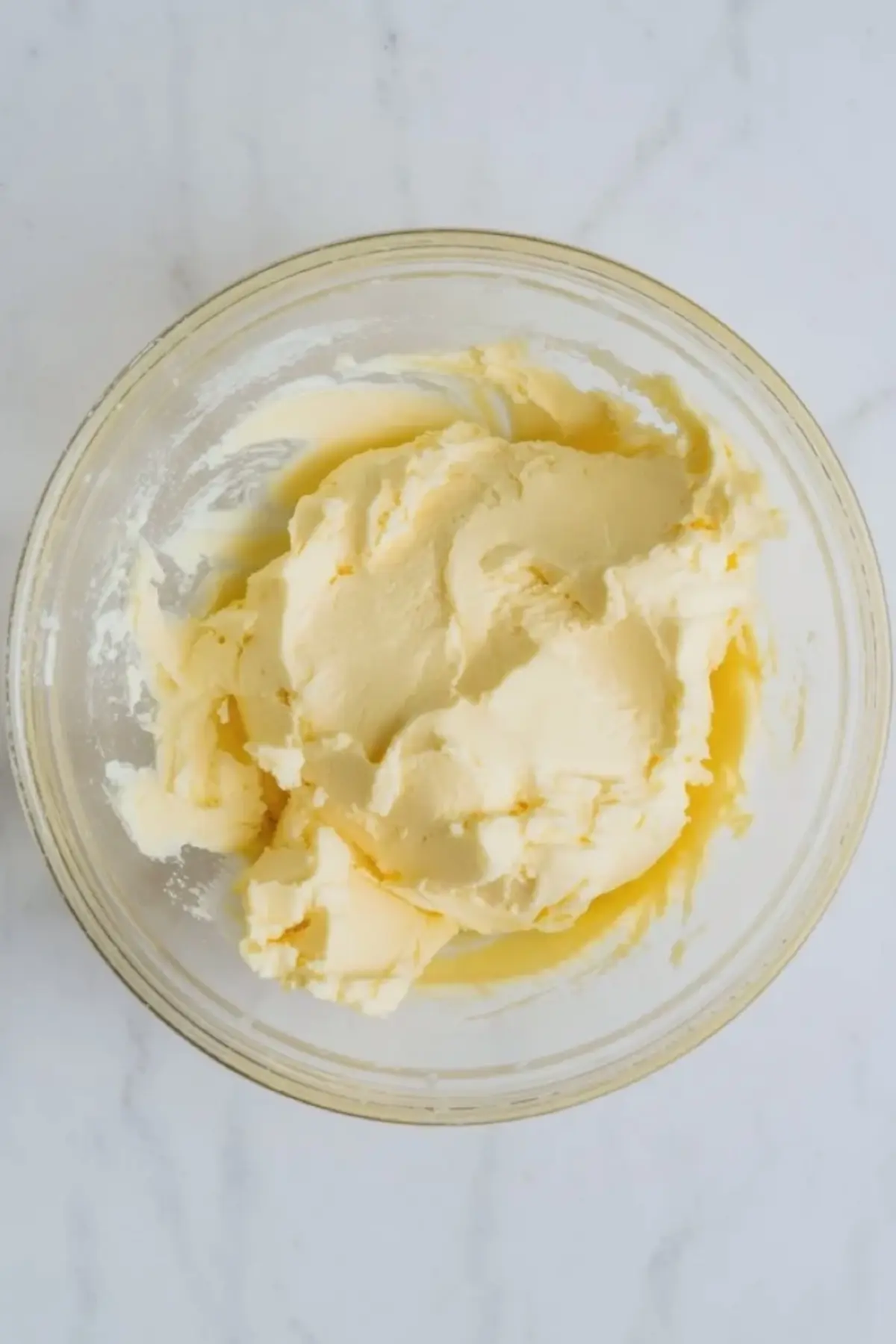 Bowl of condensed milk frosting with thick pale swirls showing the finished smooth buttercream texture before piping.