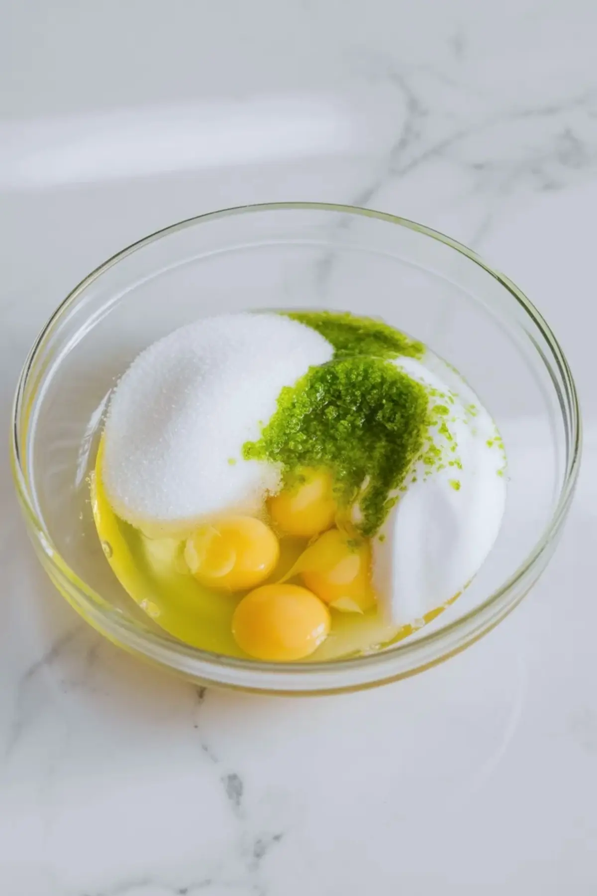 Eggs, sugar, and lime zest are mixed in a bowl at the start of making homemade lime curd.