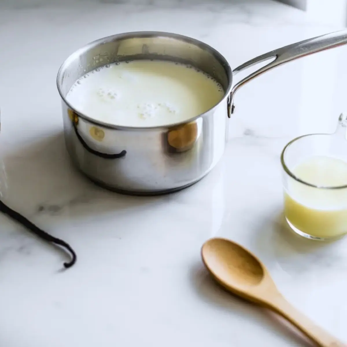 Milk and cream heating in a saucepan with vanilla for homemade matcha ice cream base preparation.